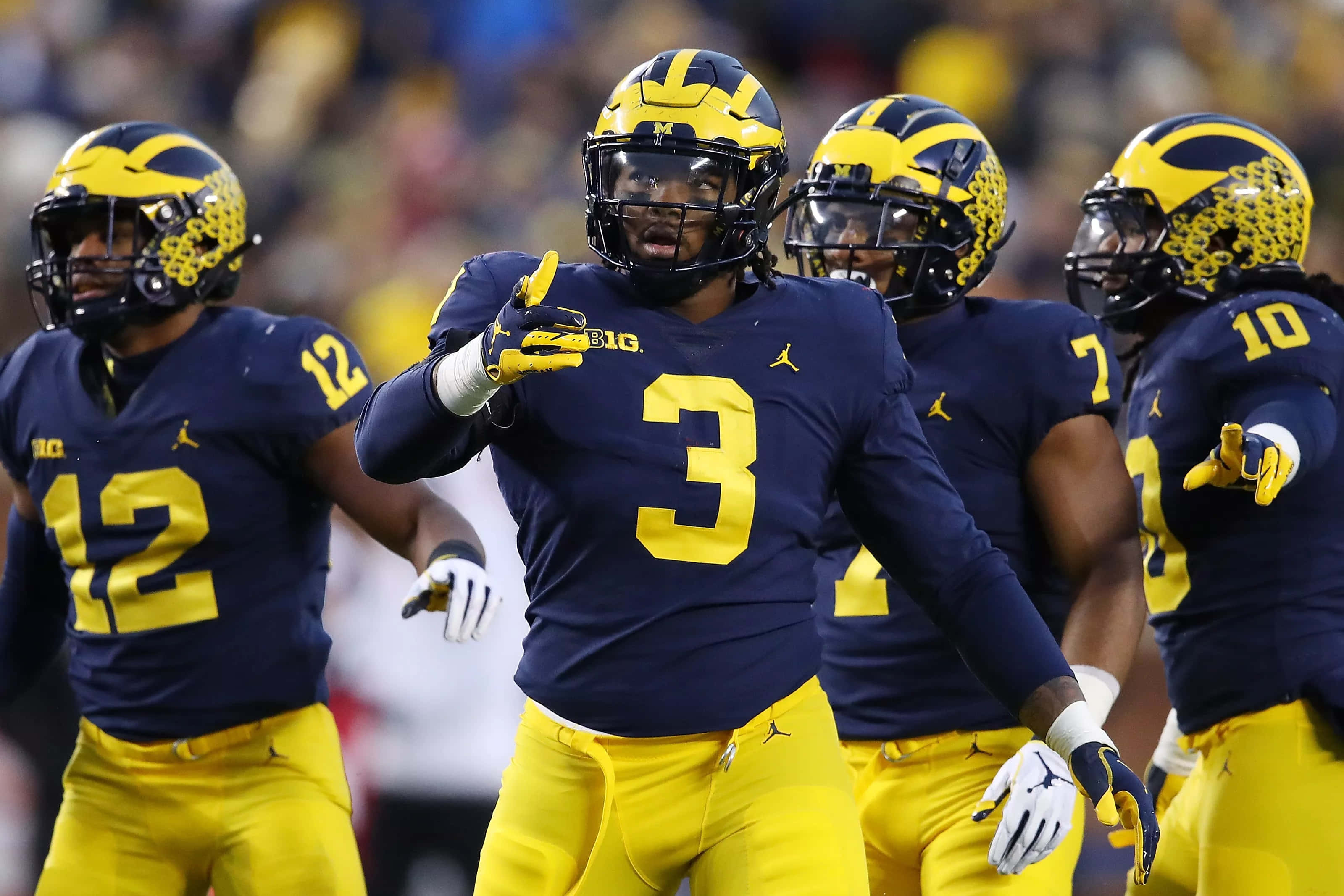 Michigan Football 桌布 壁紙 — 密西根大學美式足球員身穿海軍藍和黃色球衣，在比賽中於球場上熱烈慶祝。