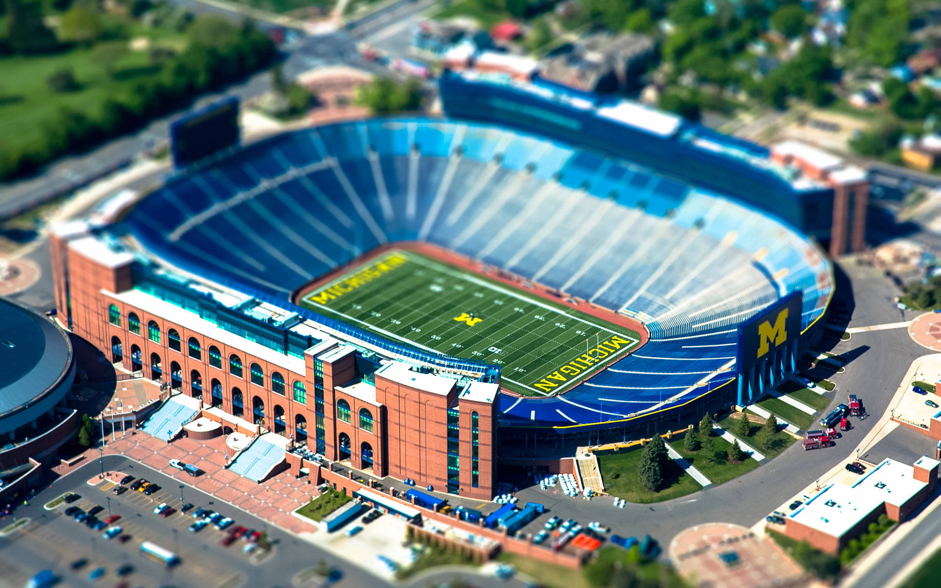Stadium 桌布 壁紙 — 密西根體育場的空中移軸攝影，展現鮮綠色場地和藍色座位，在明亮日光下。