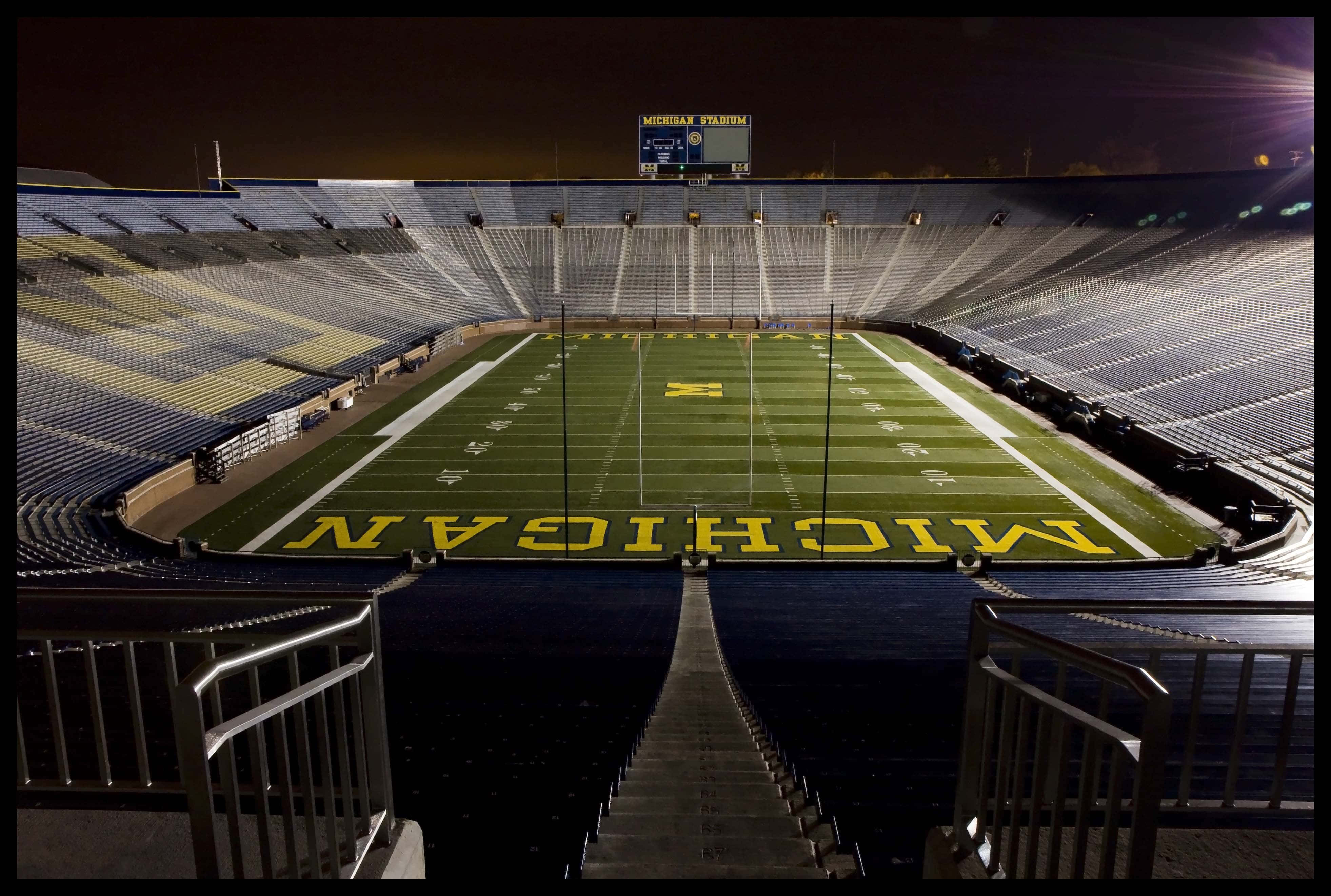 Michigan Wolverines 桌布 壁紙 — 密西根體育場空無一人的足球場在明亮體育館燈光照射下的戲劇性夜景。