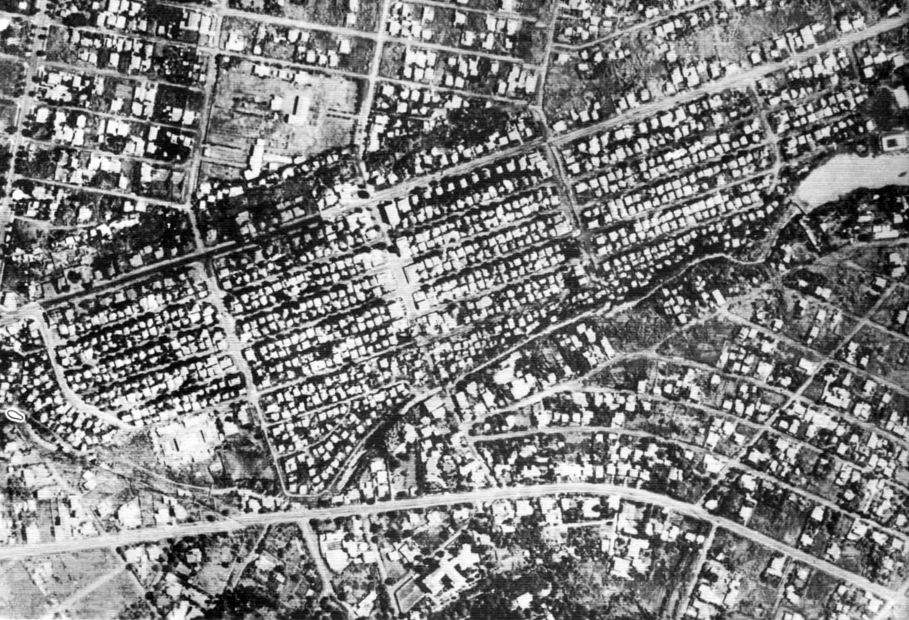 1950s 桌布 壁紙 — 密集住宅區的黑白空拍照片，街道呈棋盤狀，樹木零星散布。
