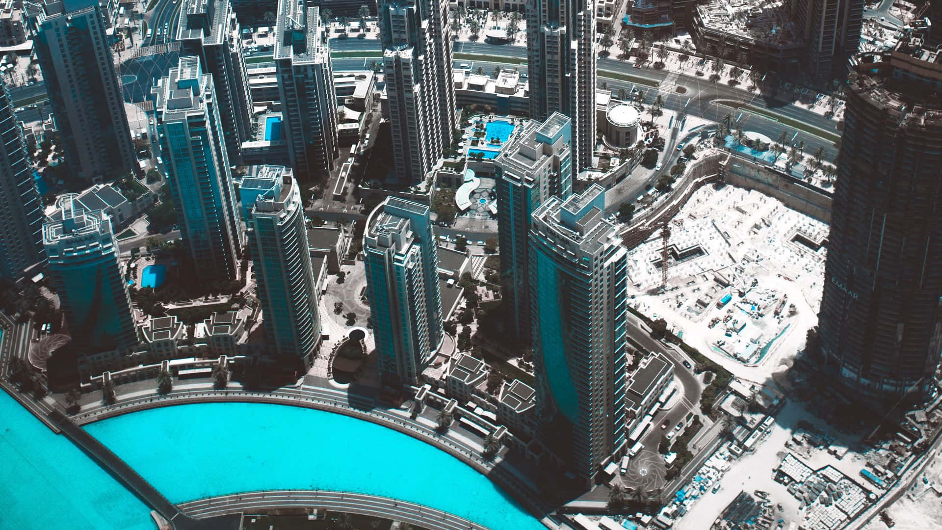 Burj Khalifa 桌布 壁紙 — 密集城市中心的未來主義摩天大樓圍繞著一個明亮的綠松石色人工湖的鳥瞰圖。