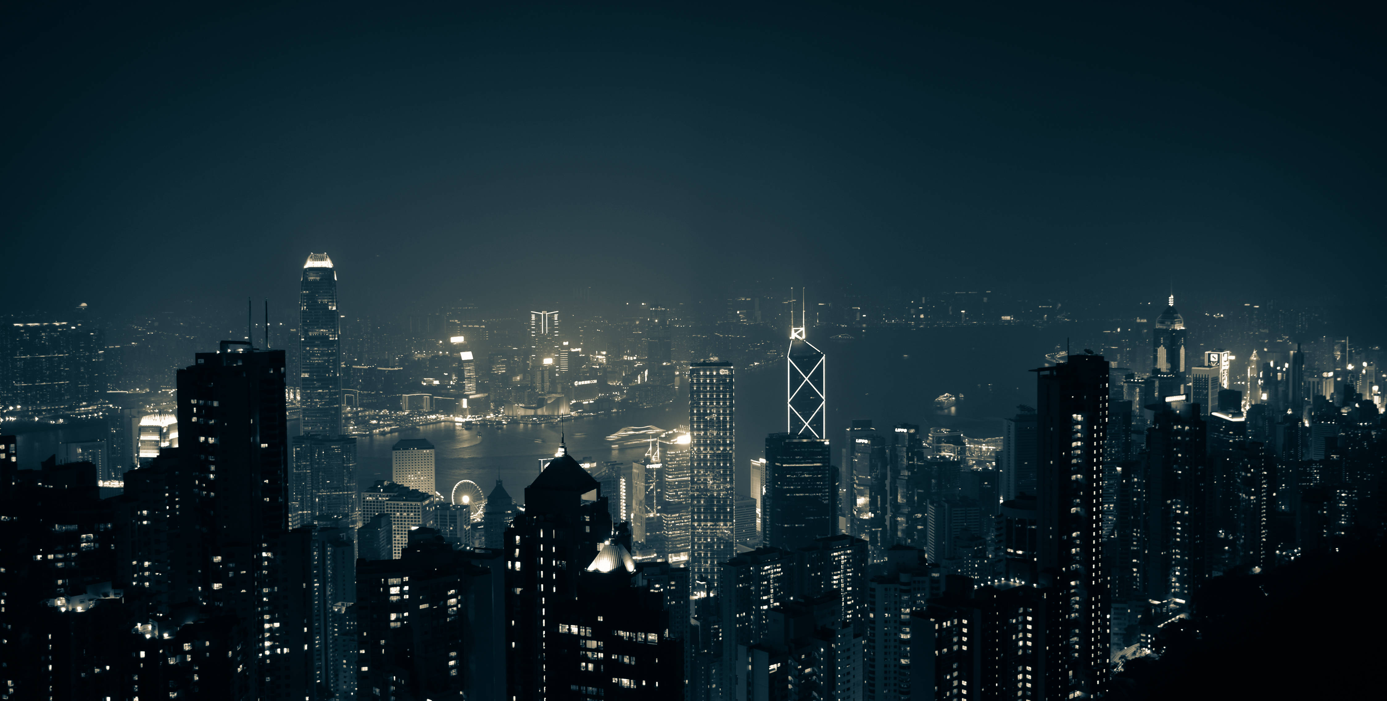 Asia 桌布 壁紙 — 密集城市天際線的 panoramic 夜景，有發光的摩天大樓和黑暗的天空。