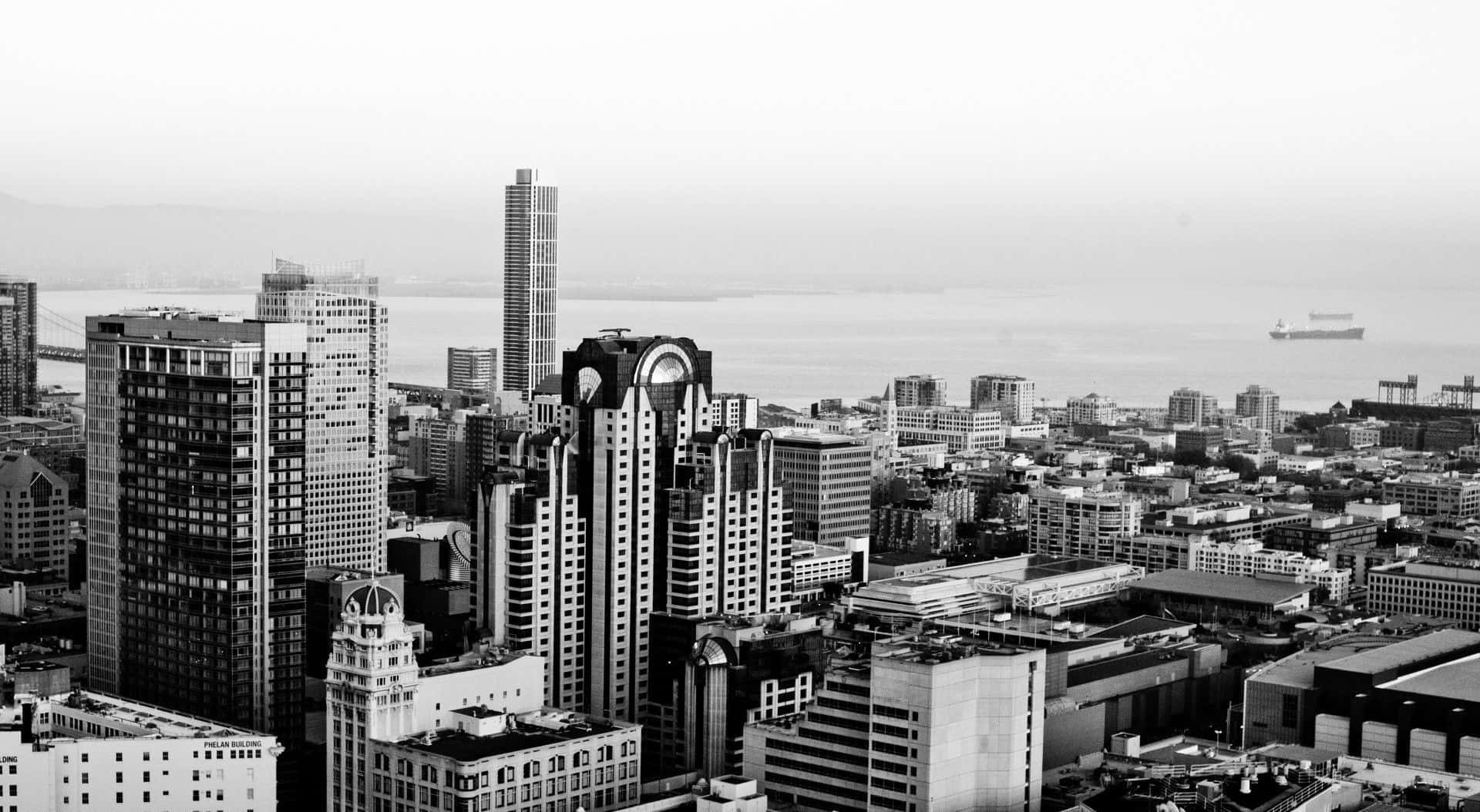 Black And White Cityscape 桌布 壁紙 — 密集城市天際線的單色航拍圖，高樓大廈林立，遠處水面上有一艘船。