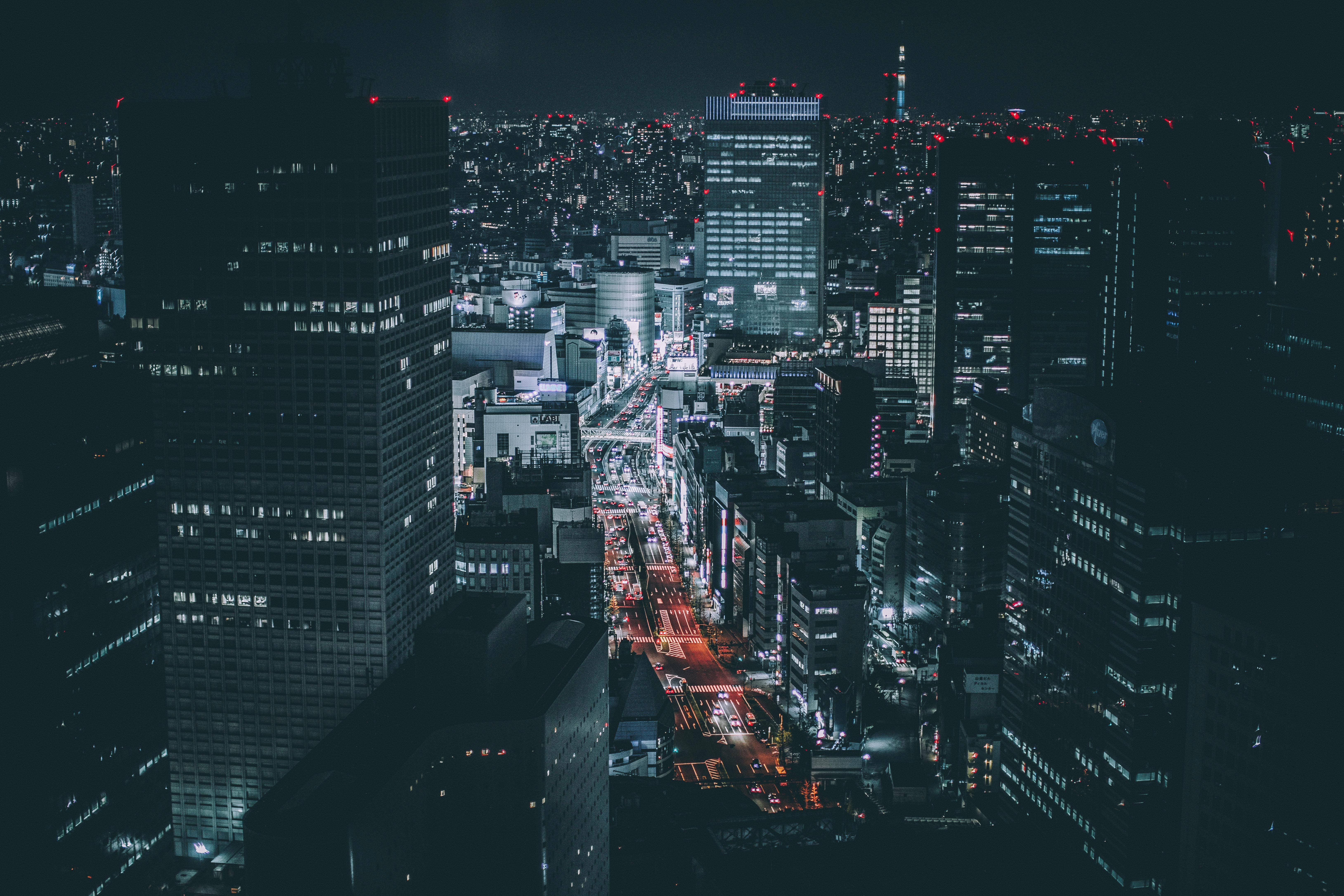 東京 桌布 壁紙 — 密集城市天際線的夜間空中景觀，發光的摩天大樓和充滿活力的路燈照亮蜿蜒的道路。