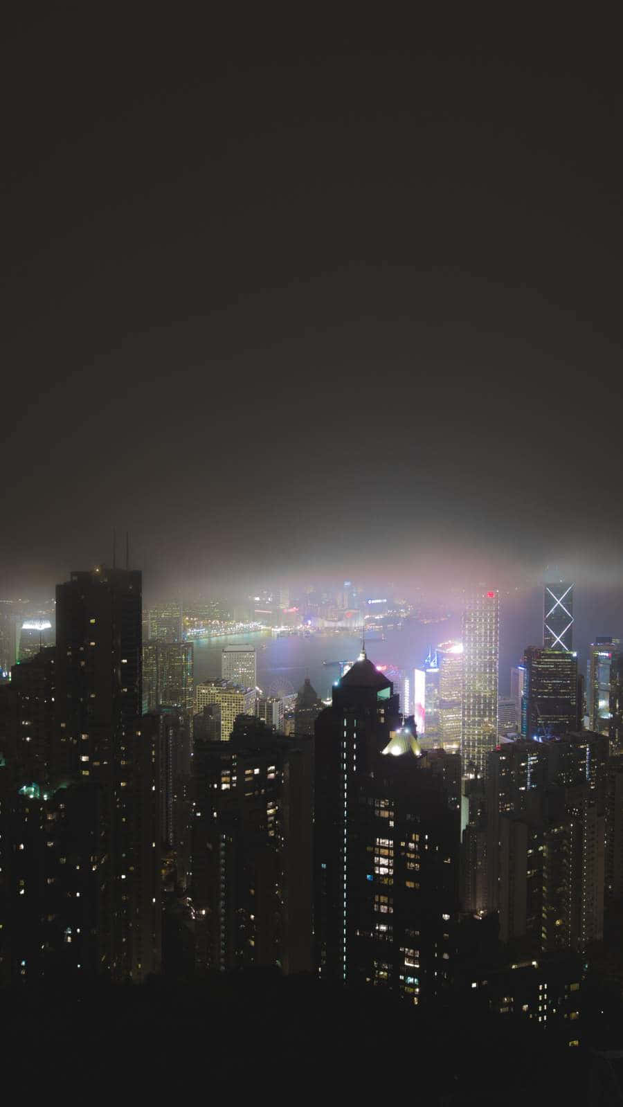 夜景城市 桌布 壁紙 — 密集城市天際線的朦朧夜景，閃爍的摩天大樓和霧氣瀰漫的地平線。