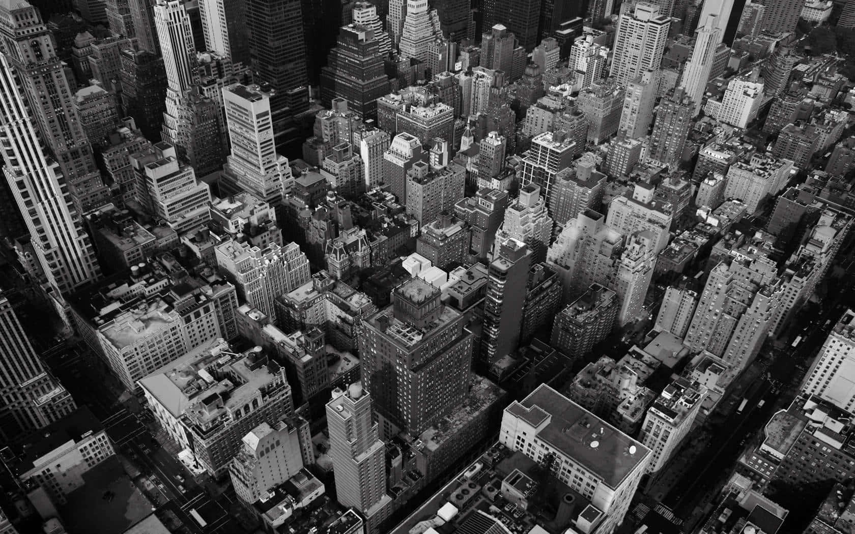 New York 桌布 壁紙 — 密集城市天際線的黑白航拍圖，高聳摩天大樓與錯綜複雜的街道圖案。