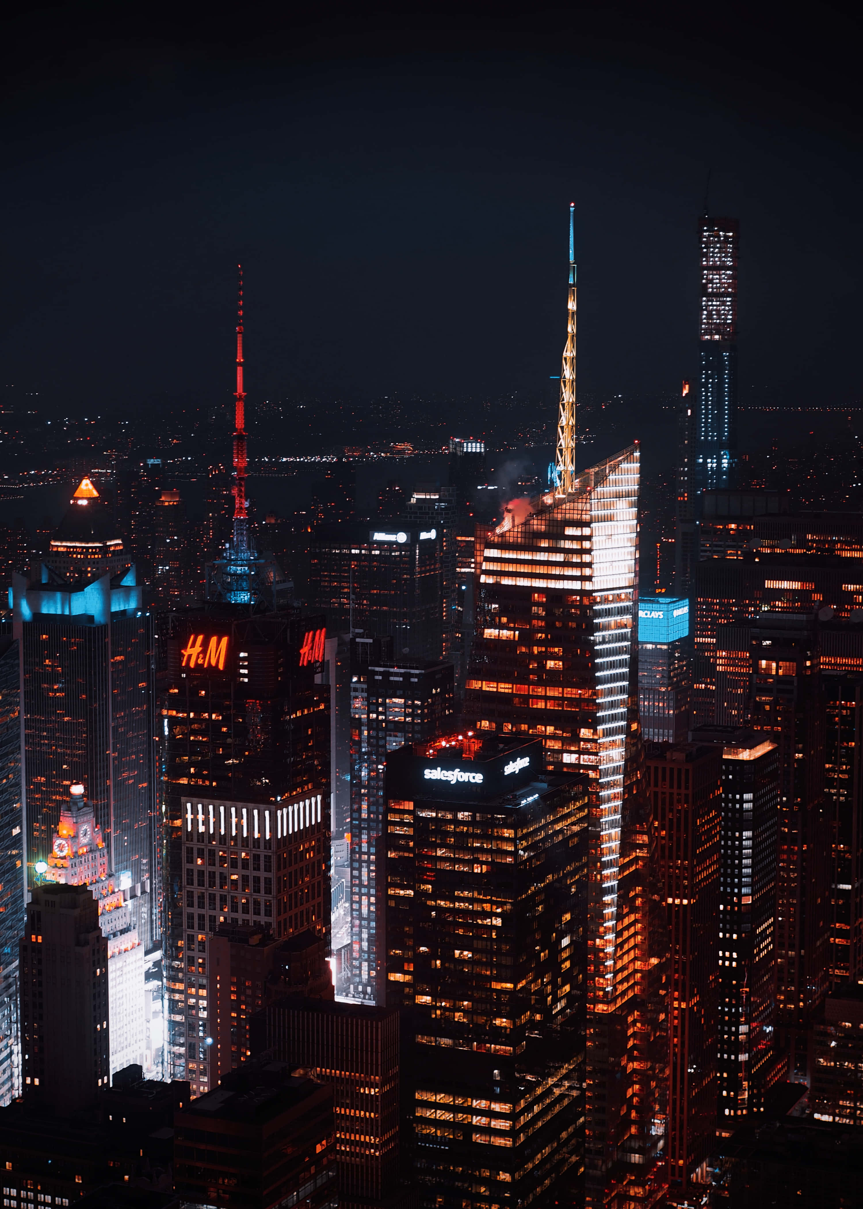 City Night 桌布 壁紙 — 密集城市景觀的空中夜景，高聳的摩天大樓在黑暗的天空中閃爍著溫暖的橙色和冷藍色的燈光。