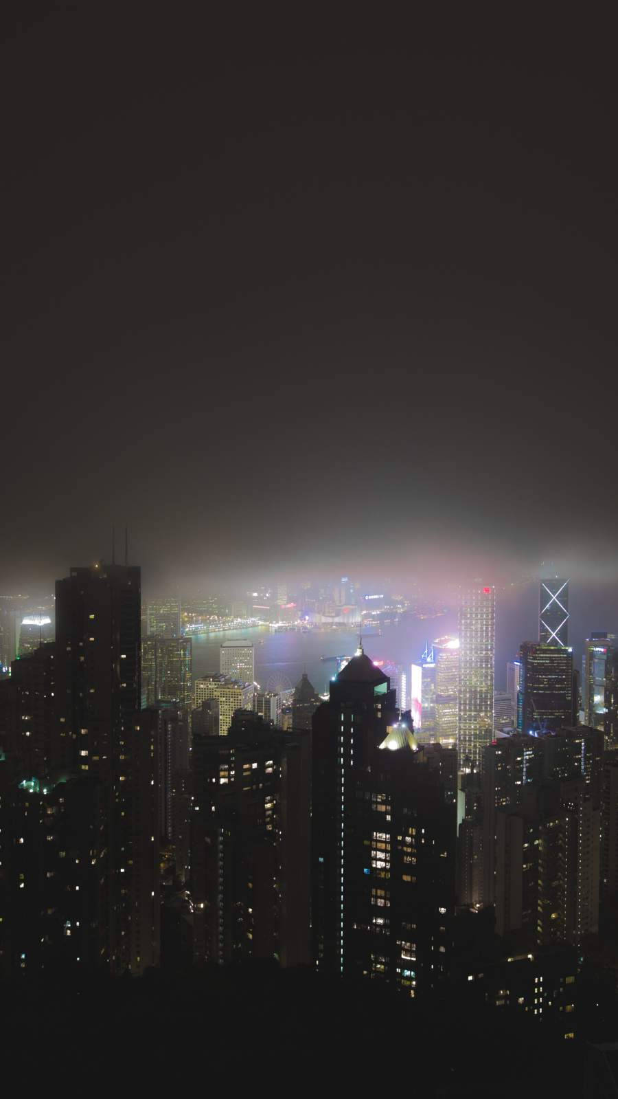桌布 壁紙 — 密集城市景觀的迷霧夜景，閃爍的摩天大樓和朦朧的地平線。