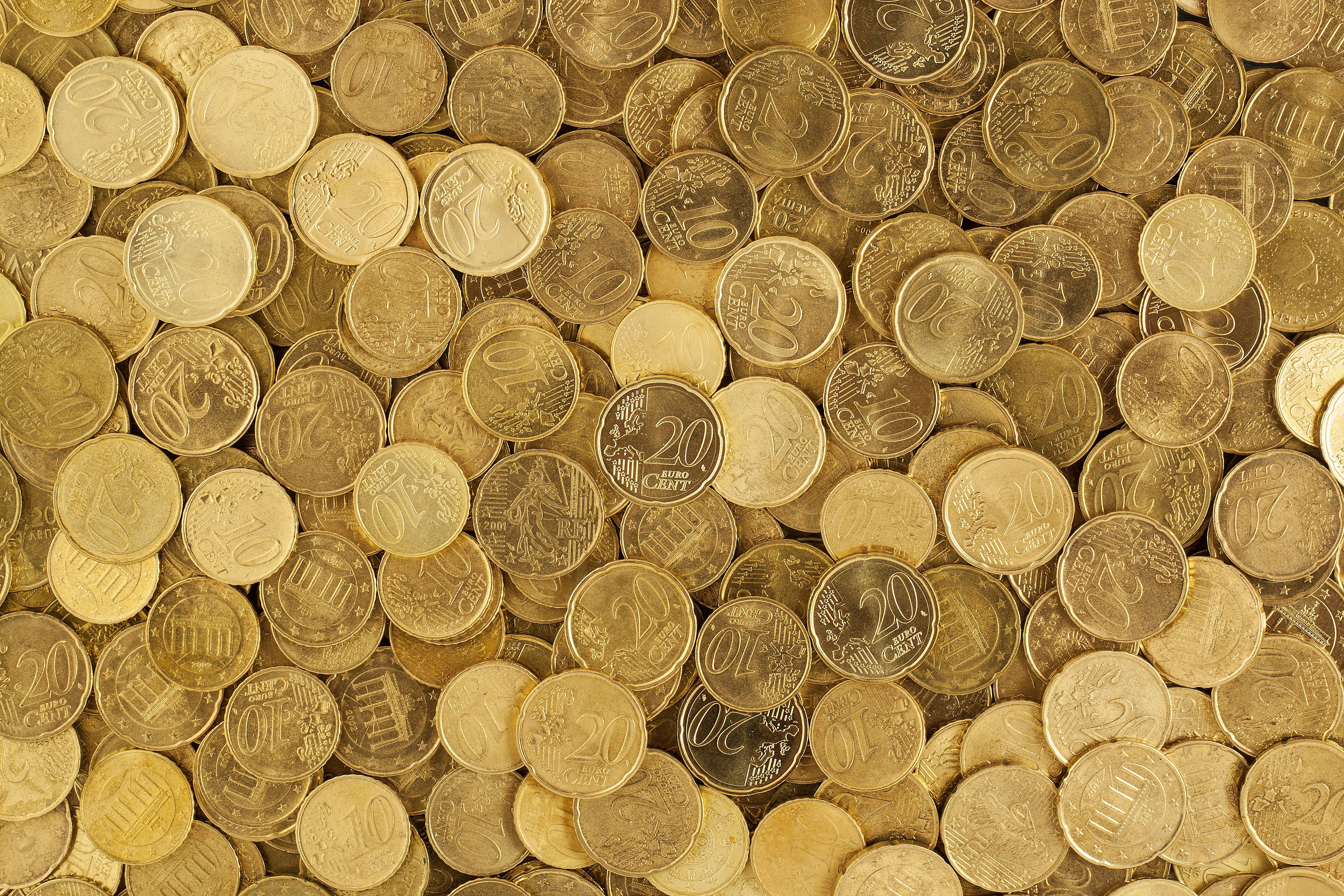 金錢 桌布 壁紙 — 密集特寫散落的歐元硬幣，呈現溫暖金色色調，面額清晰可見。