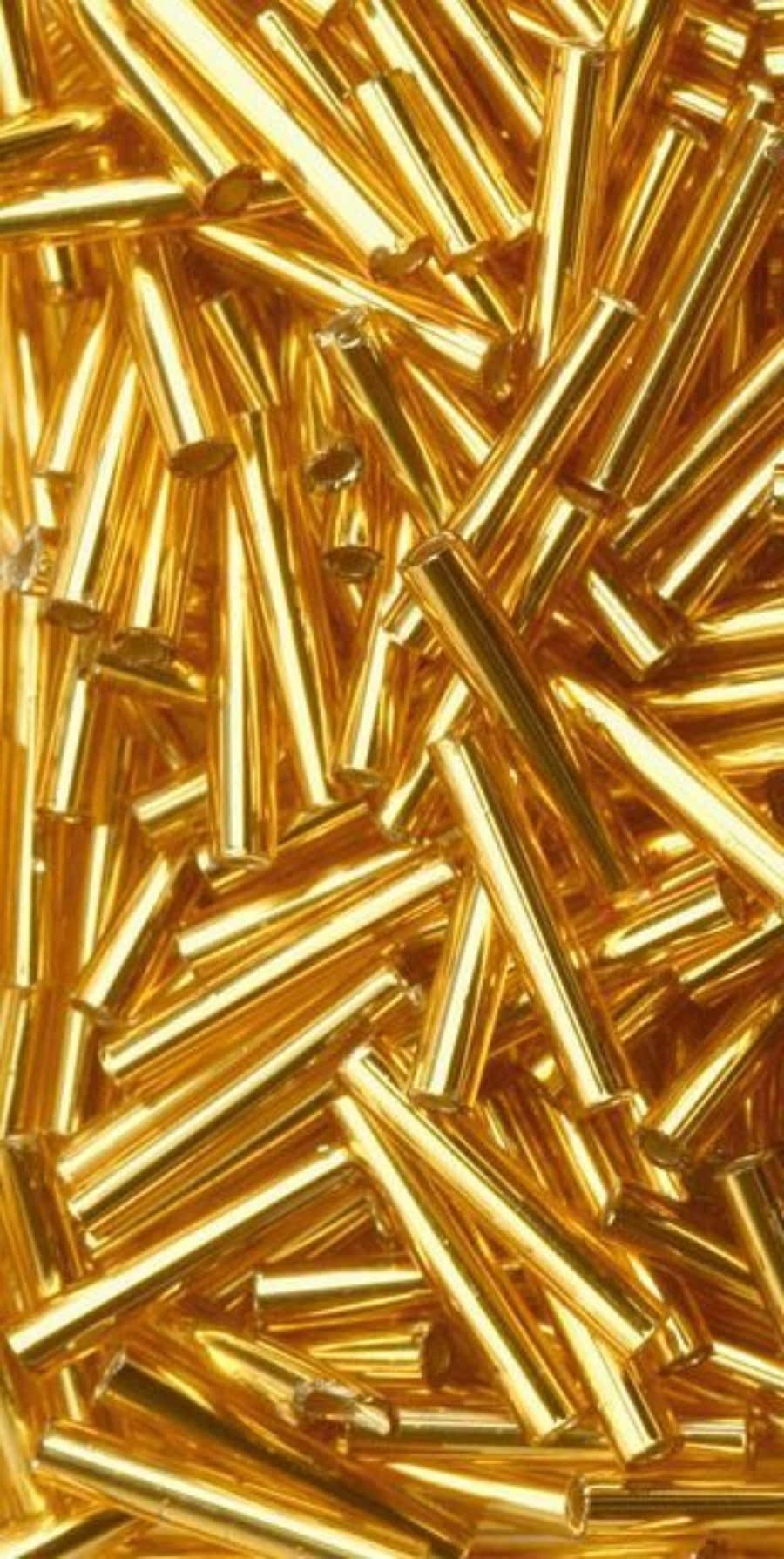 金色動態 桌布 壁紙 — 密集特寫鏡頭，展示閃亮金色圓柱形珠子以混亂、反射性排列散落。