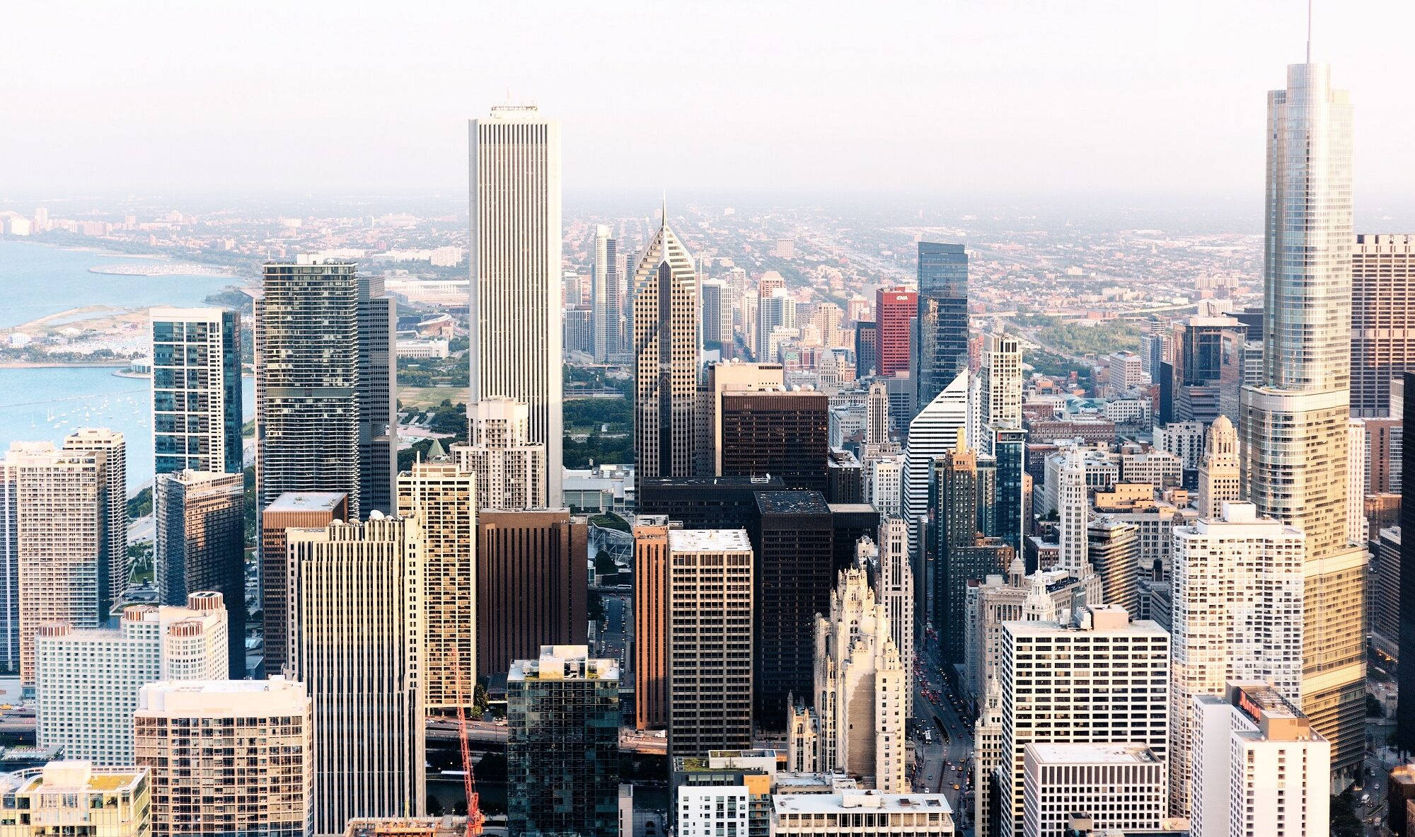 Chicago Skyline 桌布 壁紙 — 密集現代城市景觀的鳥瞰圖，高聳的摩天大樓和海濱在朦朧的日光下。