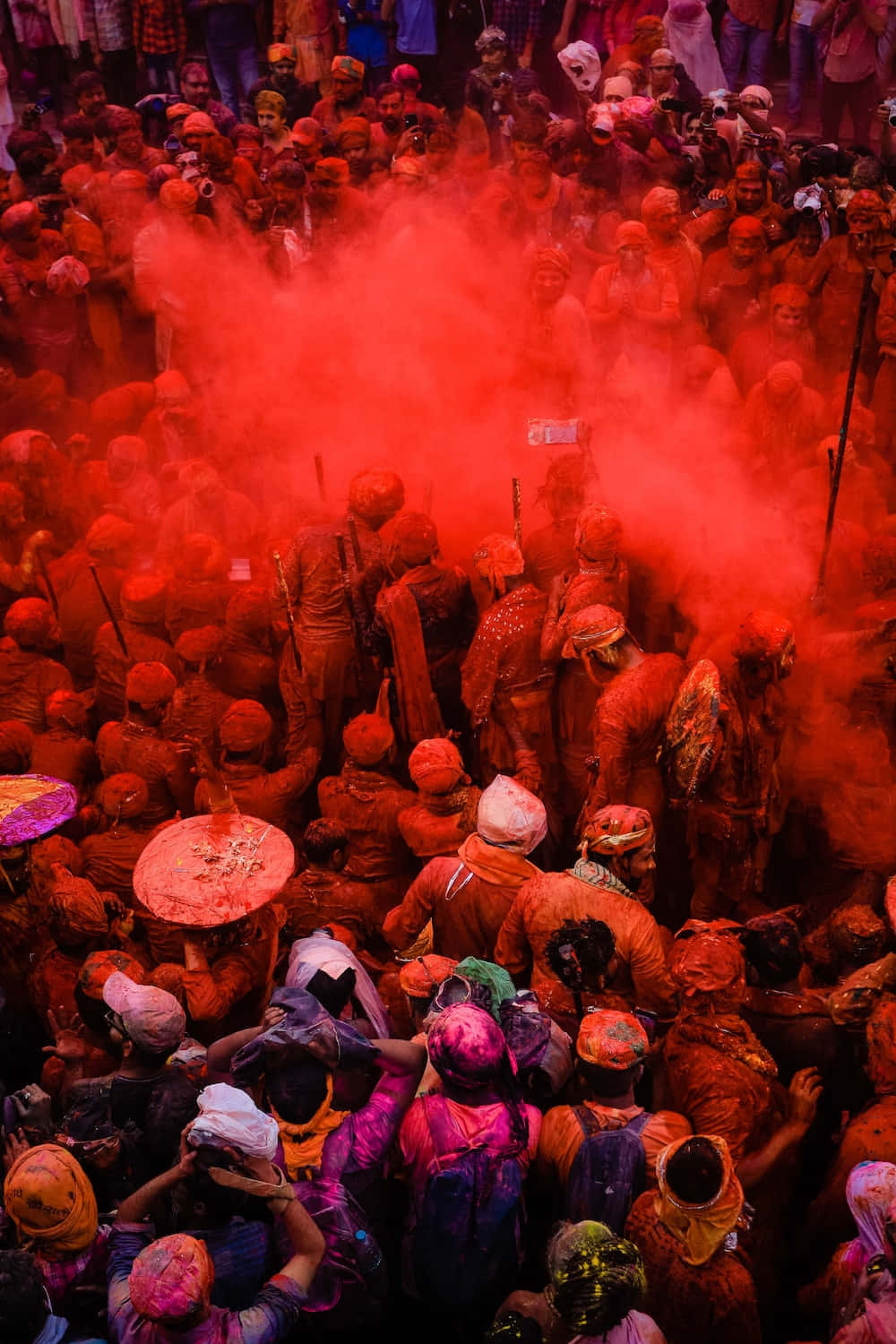 Holi 桌布 壁紙 — 密集的人群被鮮豔的紅色粉末覆蓋，在節日慶祝活動中形成濃厚的雲霧旋轉。