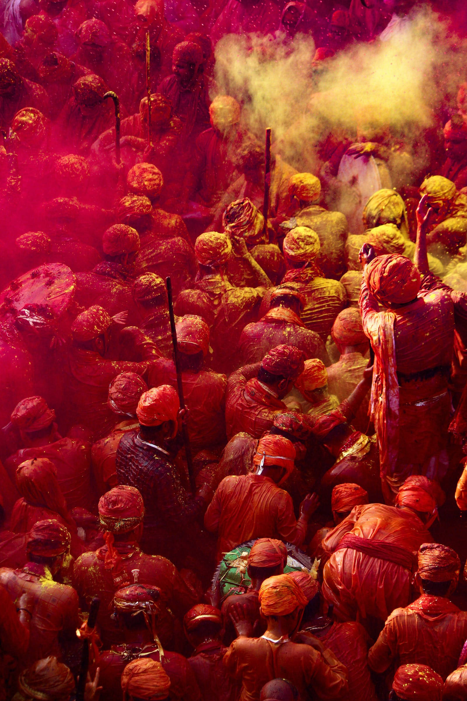 Holi 桌布 壁紙 — 密集的人群覆蓋著鮮豔的紅色和黃色粉末，在節日慶祝活動中空氣中旋轉著灰塵。