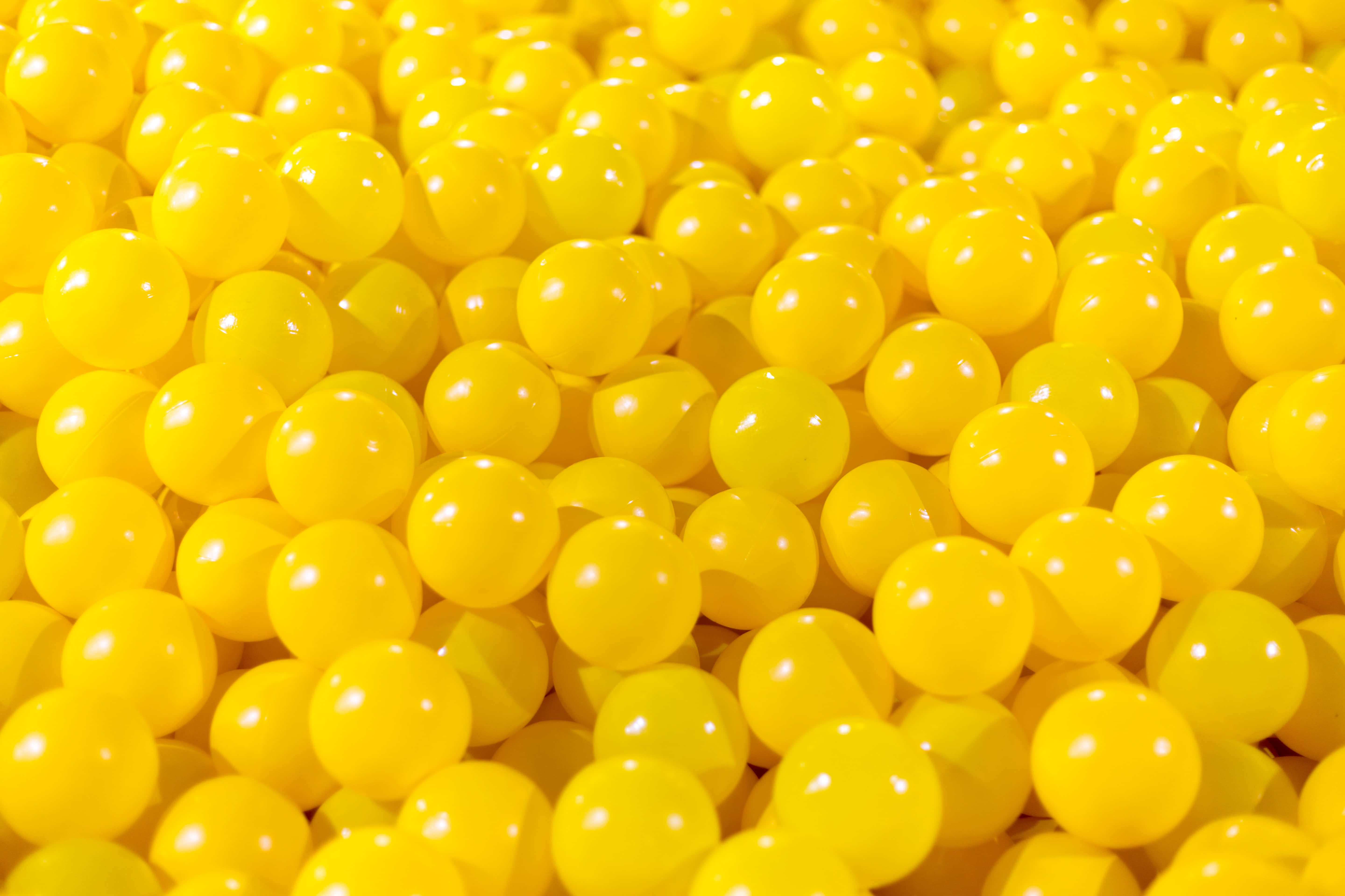 balls 桌布 壁紙 — 密集的光澤黃色塑膠球充滿了畫面，呈現出鮮豔且反射的表面。