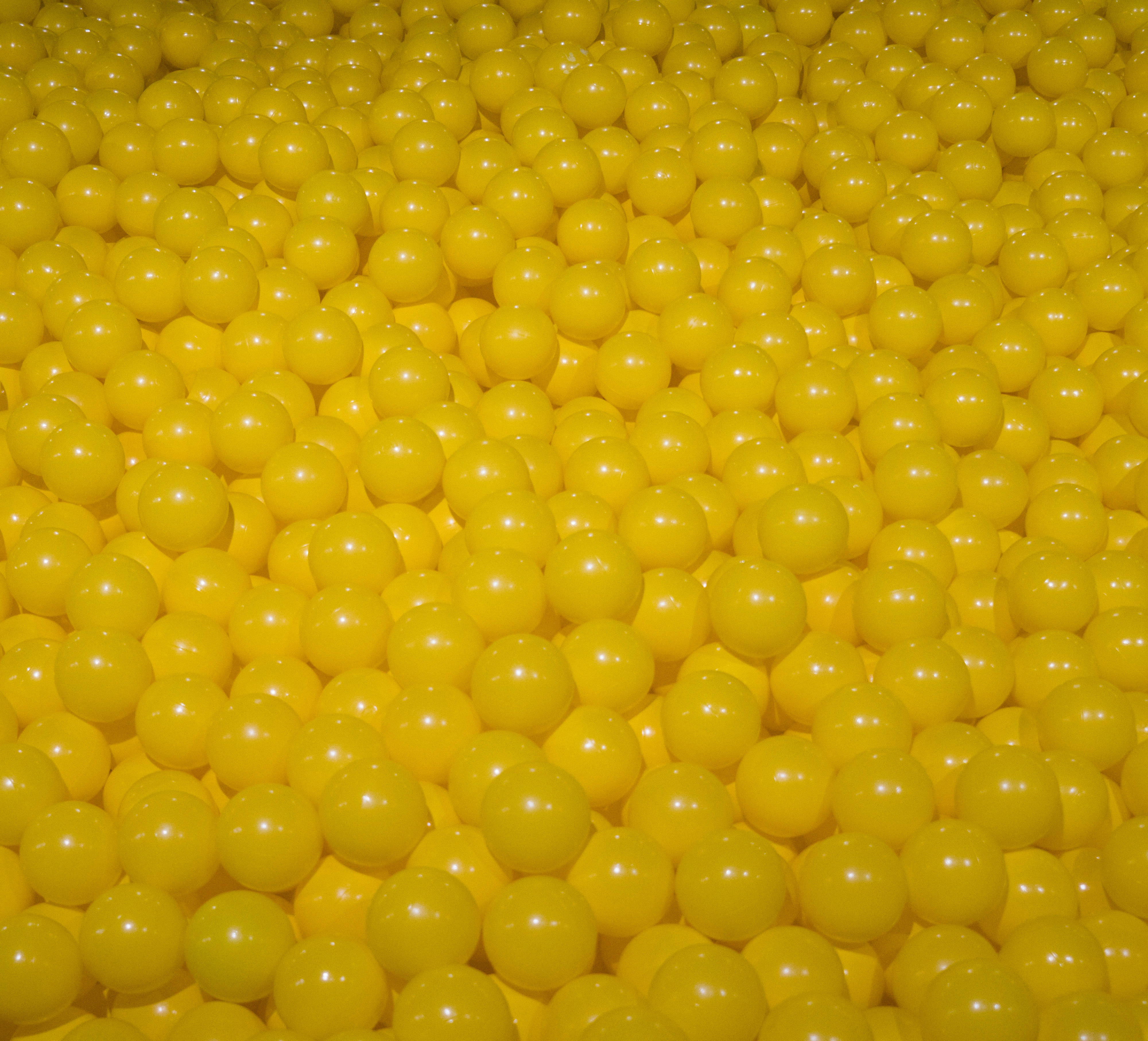 the yellow 桌布 壁紙 — 密集的光澤黃色塑膠球充滿畫面，呈現均勻的球形和柔和的高光。