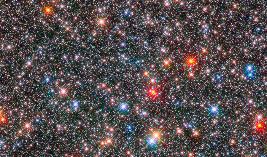 太空 桌布 壁紙 — 密集的彩色星星在深邃黑色宇宙背景下閃爍，帶有鮮豔的紅色、藍色和白色恆星耀斑。