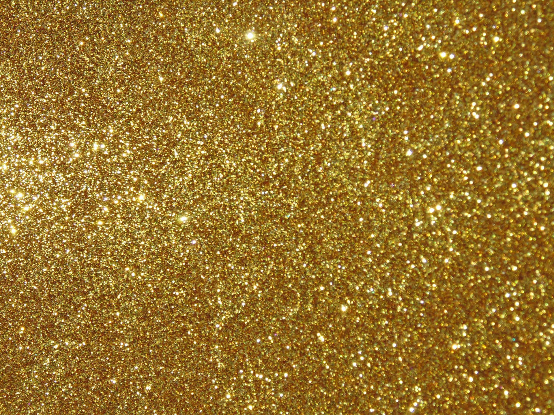 High Resolution Gold Glitter 桌布 壁紙 — 密集的金色亮粉粒子在光線下閃爍，形成光彩奪目、帶有紋理的閃光效果。