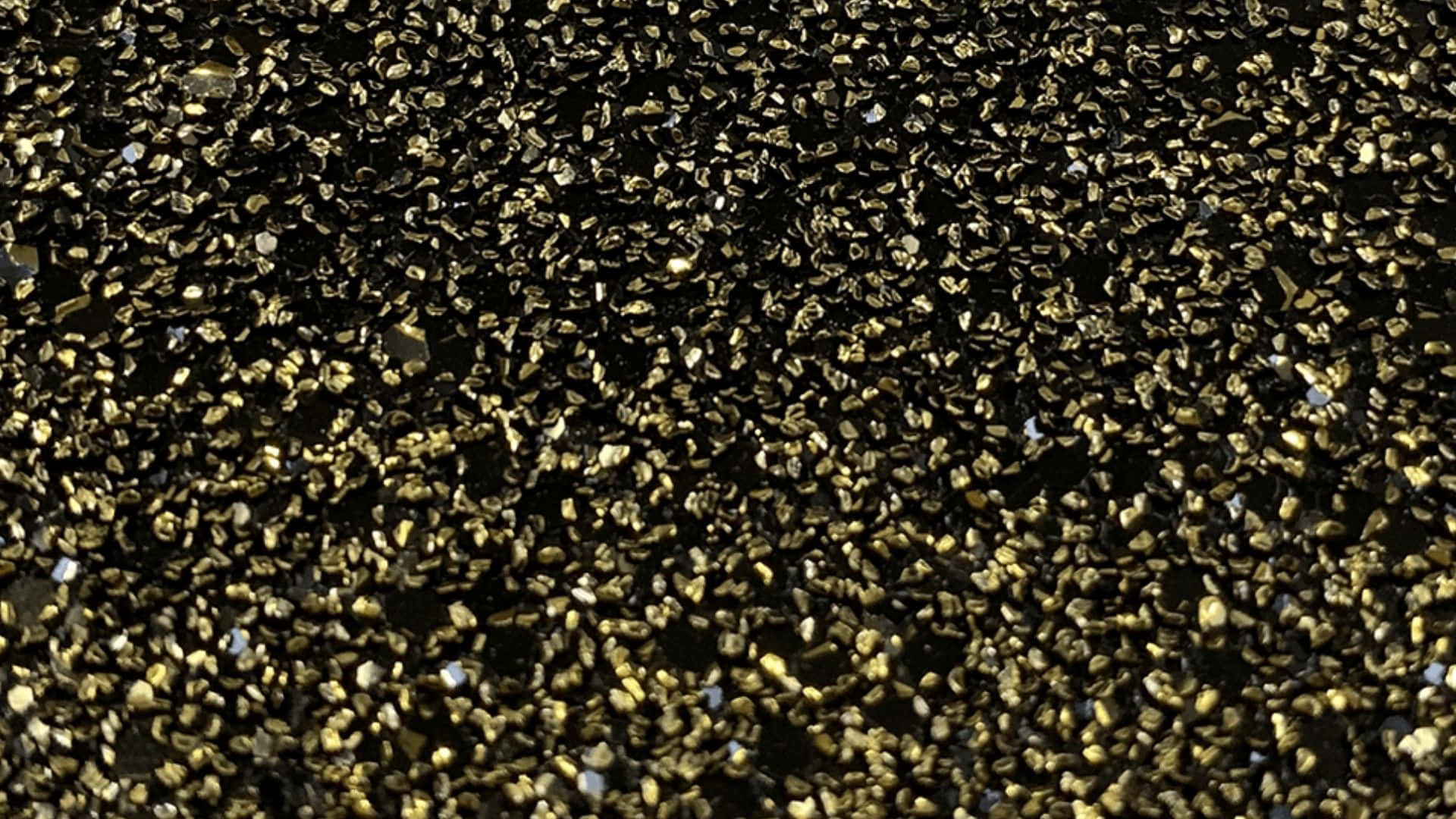 High Resolution Glitter 桌布 壁紙 — 密集的金色閃粉粒子散佈在深色背景上，營造出閃閃發光的紋理表面。