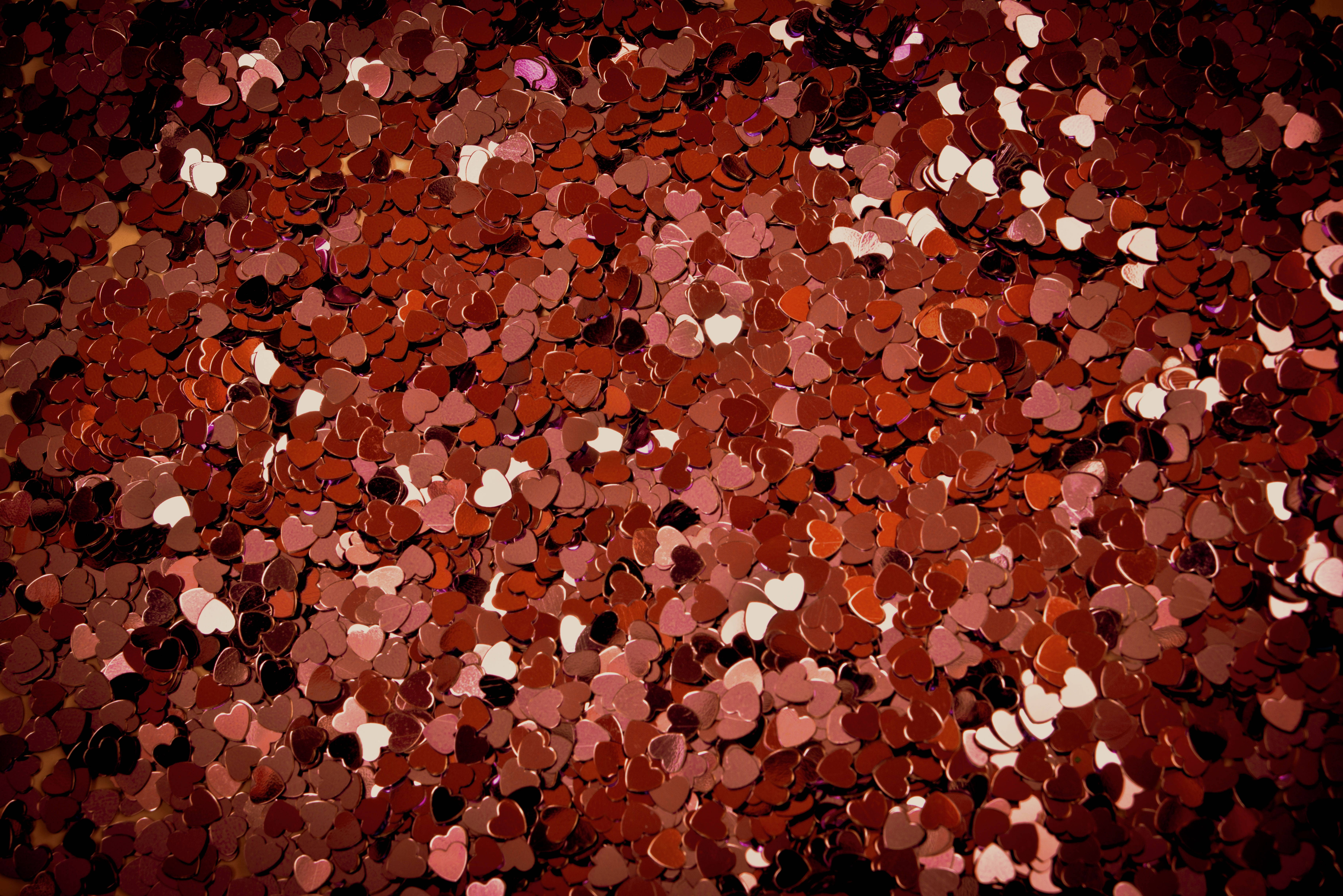 Love Heart 桌布 壁紙 — 密集的閃爍紅色和粉紅色心形紙屑營造出浪漫又喜慶的紋理背景。