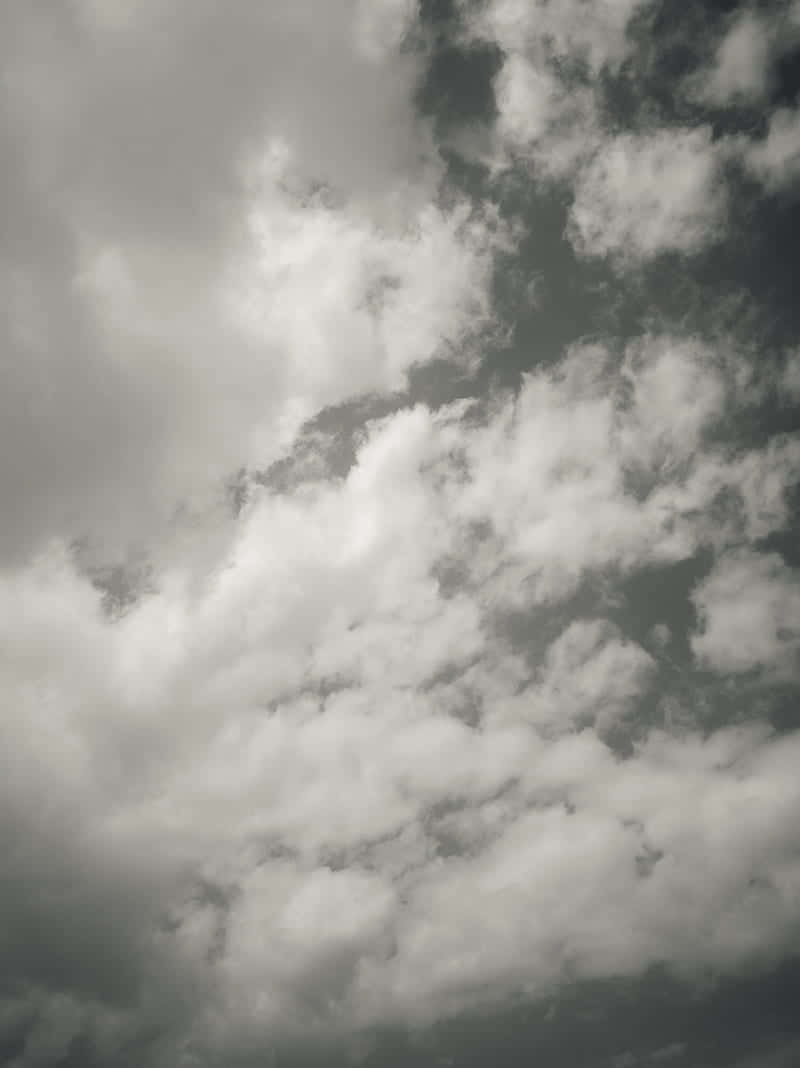 Cloudy 桌布 壁紙 — 密集蓬鬆的白雲在陰沉的灰色天空中飄移，形成戲劇性的俯拍鏡頭。