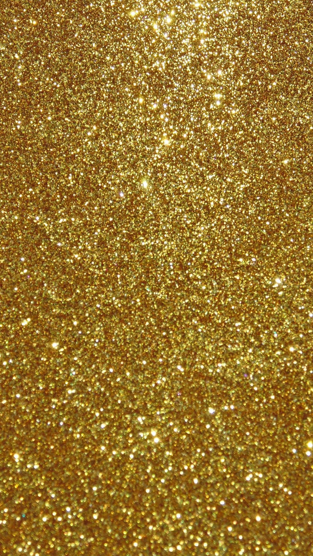Gold Glitter 桌布 壁紙 — 密集閃爍的金色亮粉顆粒在光線下呈現出光彩奪目、有紋理的光芒。