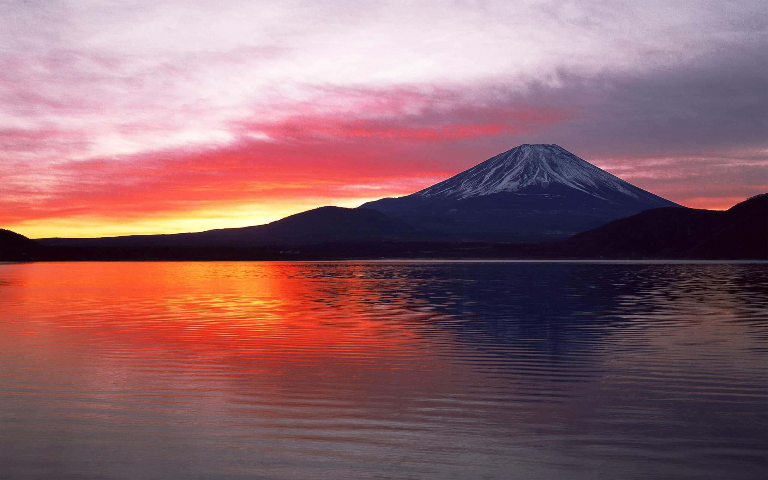 富士山 桌布 壁紙 — 富士山在平靜的水面上倒映，天空是火燒般的日落，帶有粉紅、橙色和紫色的雲彩。