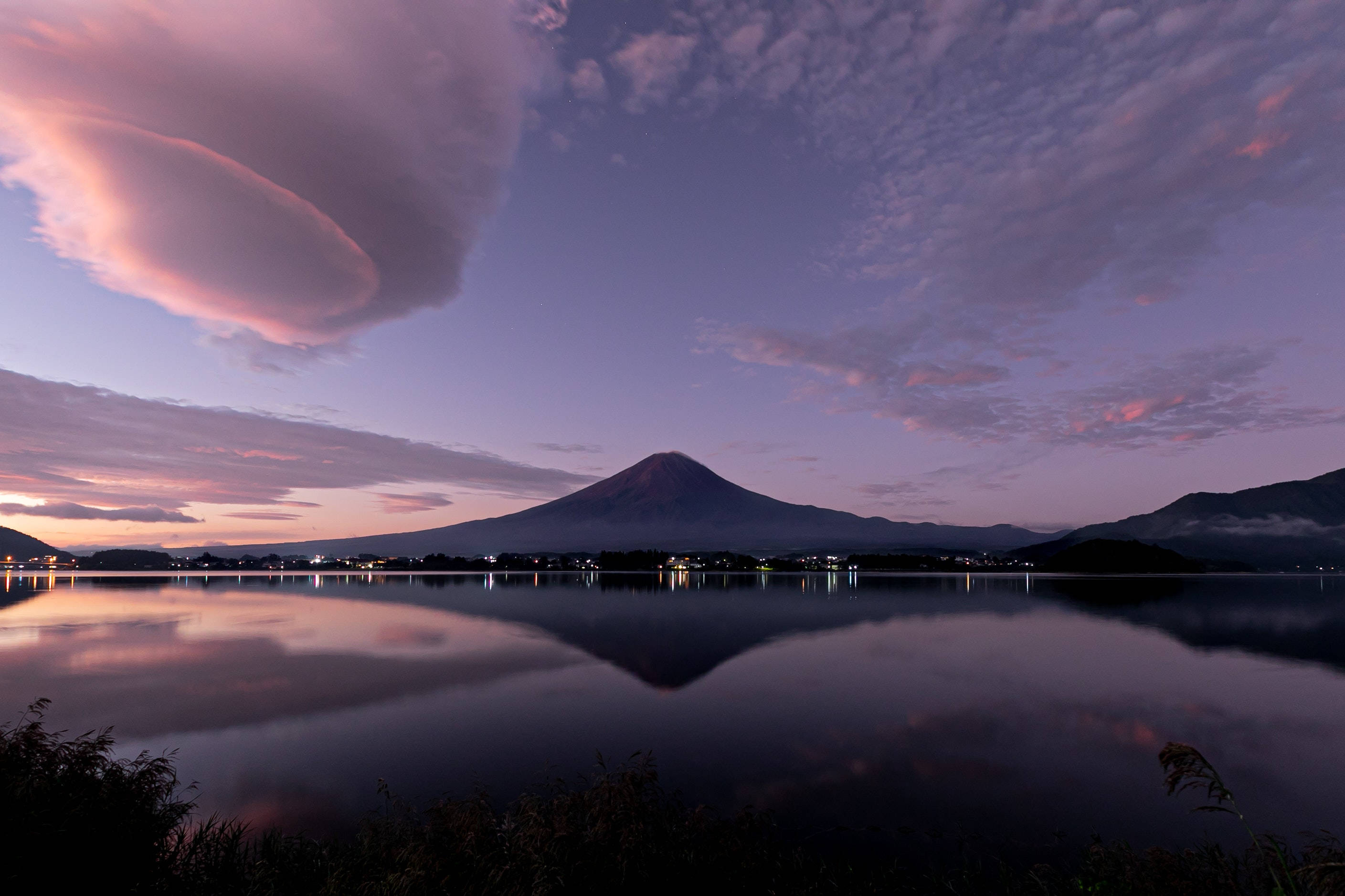 富士山 桌布 壁紙 — 富士山在戲劇性的紫色和粉紅色暮色天空下，完美地倒映在平靜的水面上。