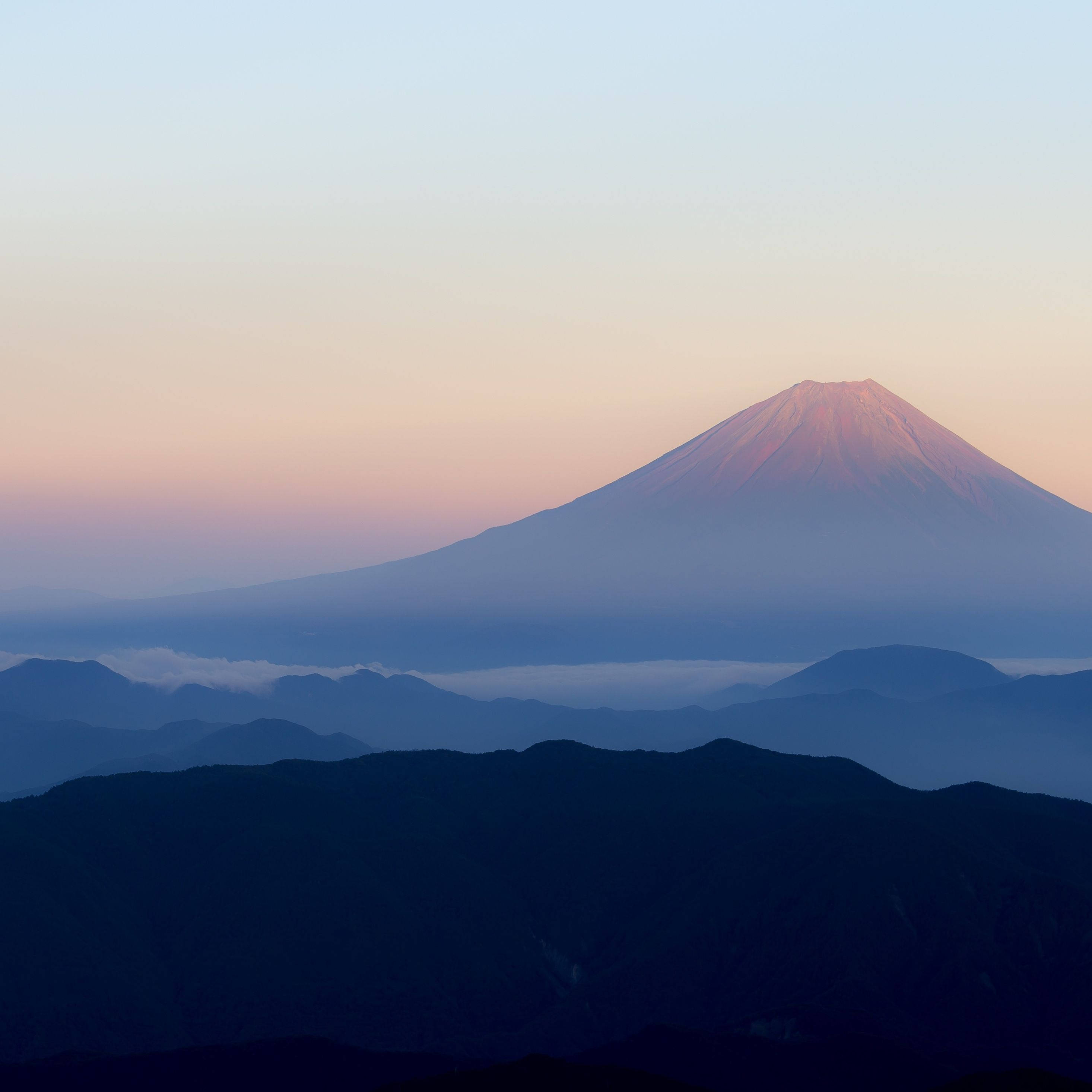 Silhouette 桌布 壁紙 — 富士山在黎明時分雄偉地升起，柔和的粉紅色和藍色調在層疊的山巒輪廓上空繪出天空。