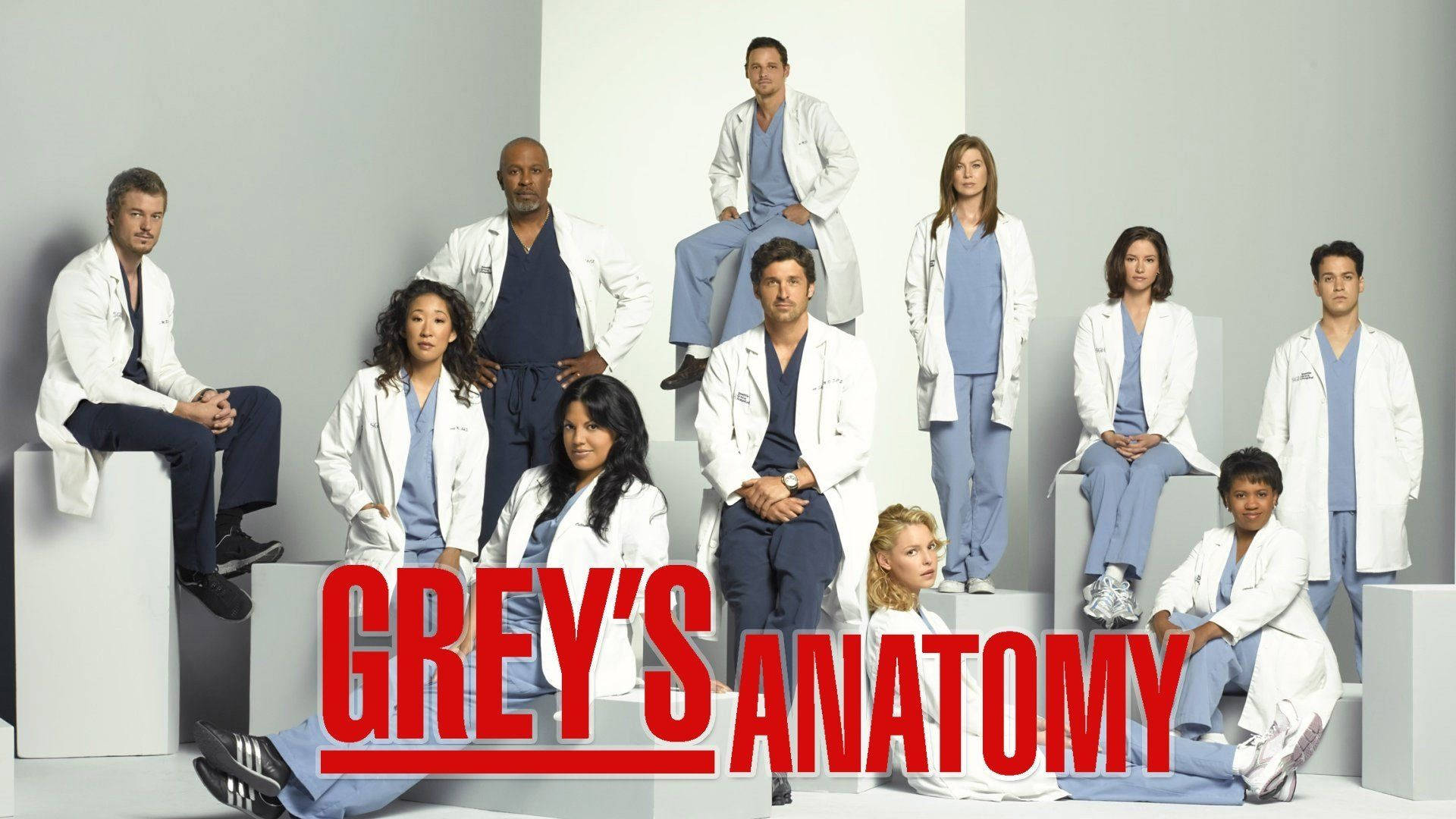 anatomy 桌布 壁紙 — 《實習醫生》演員身穿臨床手術服和實驗室外套，在白色方塊上擺姿勢，背景為簡約工作室。