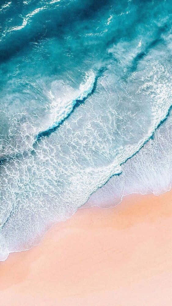 Aesthetic Wave 桌布 壁紙 — 寧靜海岸場景中，碧綠海浪拍打柔軟蜜桃色沙灘的航拍視角。