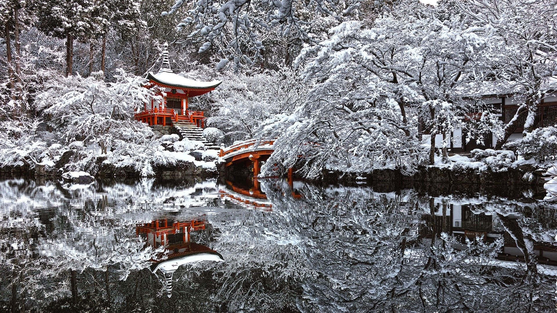 High Resolution Snow 桌布 壁紙 — 寧靜的冬日景色，一座鮮紅色的日本寶塔和橋樑倒映在平靜的水面上，周圍是白雪覆蓋的樹木。