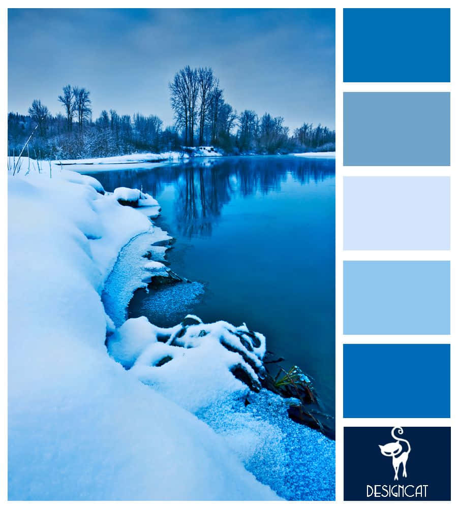 Ice Blue 桌布 壁紙 — 寧靜的冬日河岸，白雪覆蓋的河岸和光禿的樹木倒映在暮色天空下平靜的藍色水面上。