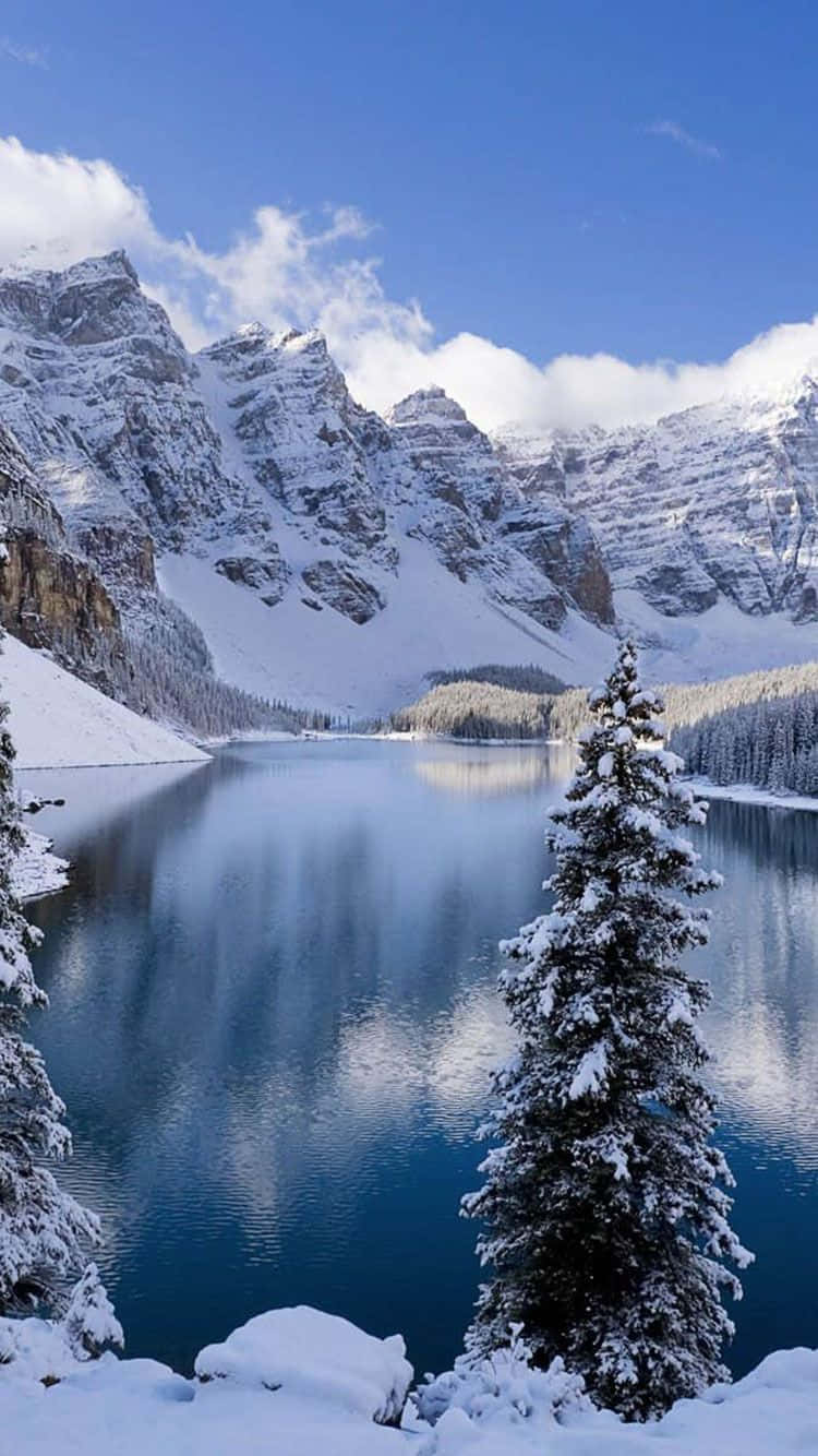 Winter Scene 桌布 壁紙 — 寧靜的冬日湖泊在晴朗藍天和蓬鬆白雲下，倒映著積雪覆蓋的山峰。