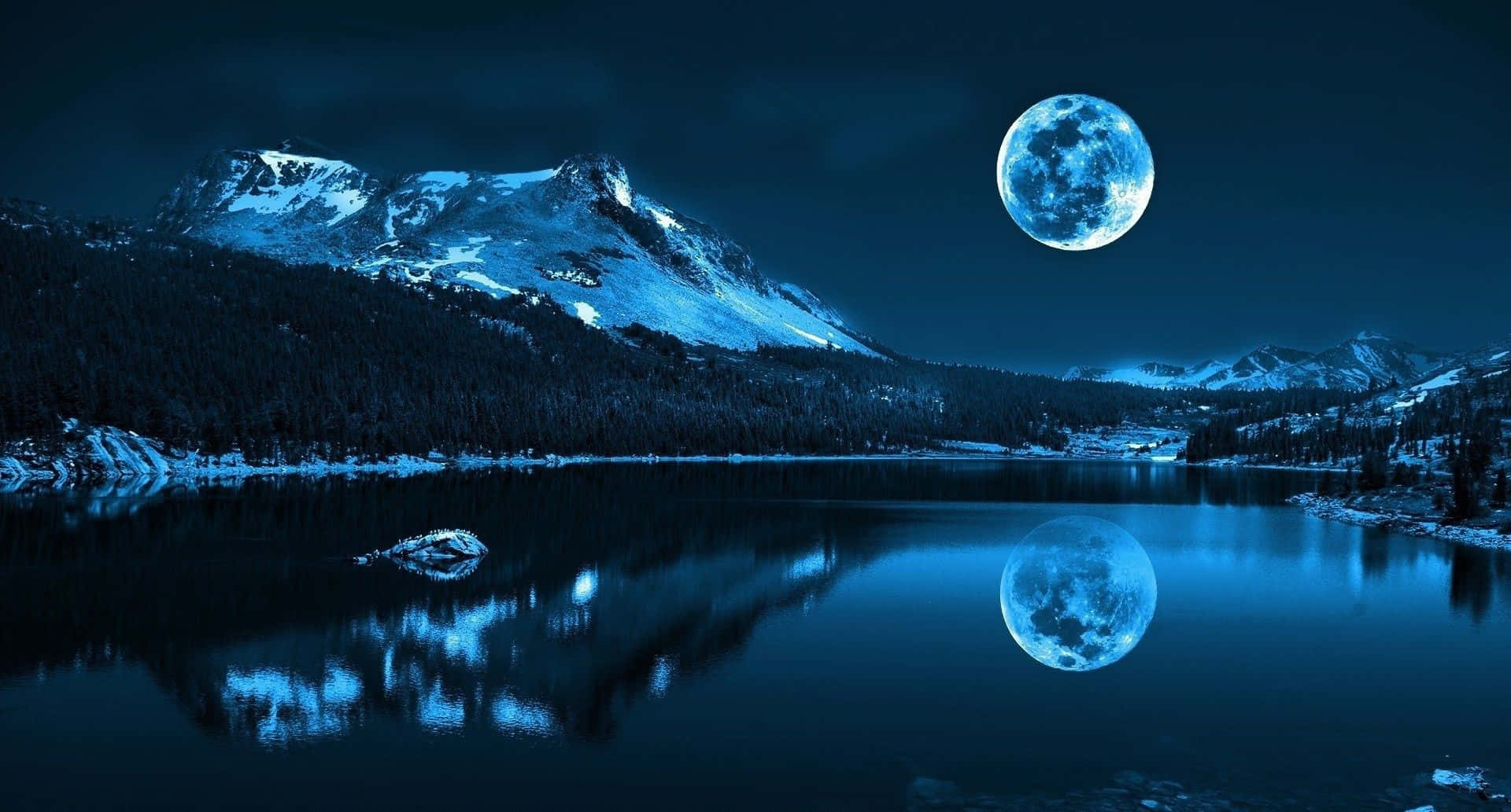 Moonlight 桌布 壁紙 — 寧靜的冬日湖泊映照著暗藍夜空下積雪山峰上巨大的發光月亮。
