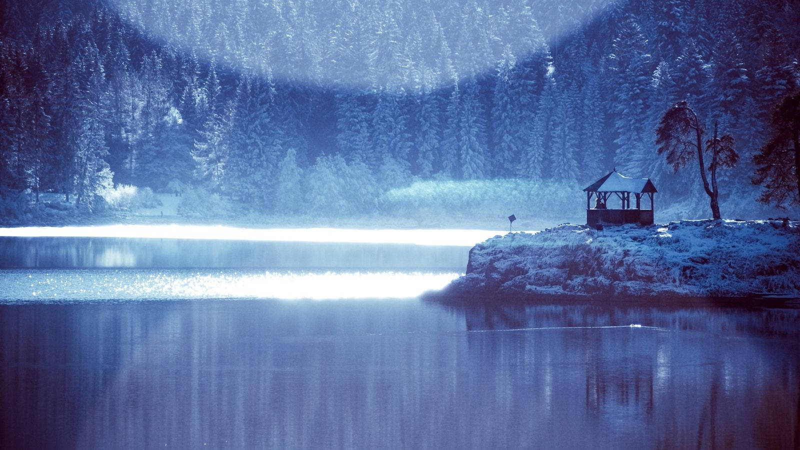 Blue Aesthetic Desktop 桌布 壁紙 — 寧靜的冬日湖泊映照著雪覆蓋的森林和孤獨的涼亭，在柔和的藍色暮色天空下。