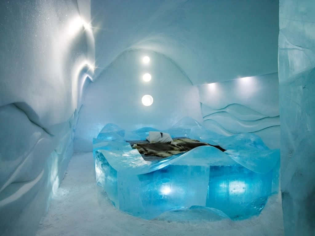 Ice Hotel 桌布 壁紙 — 寧靜的冰酒店房間，發光的藍色牆壁和一張由半透明冰雕刻而成的床，在柔和的天花燈光下。