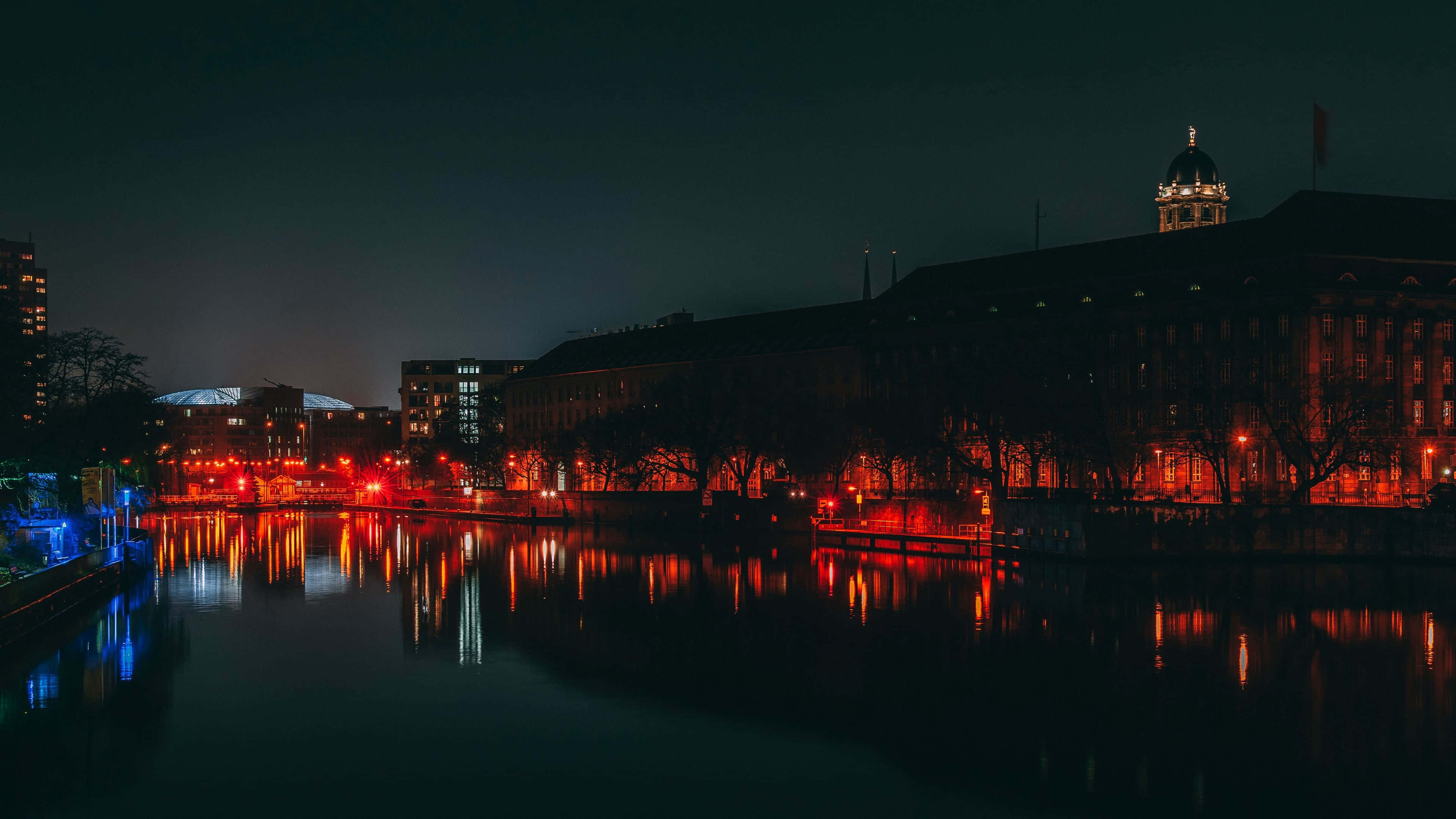 德國 桌布 壁紙 — 寧靜的夜景，溫暖的紅燈映照在歷史建築旁的平靜水面上。