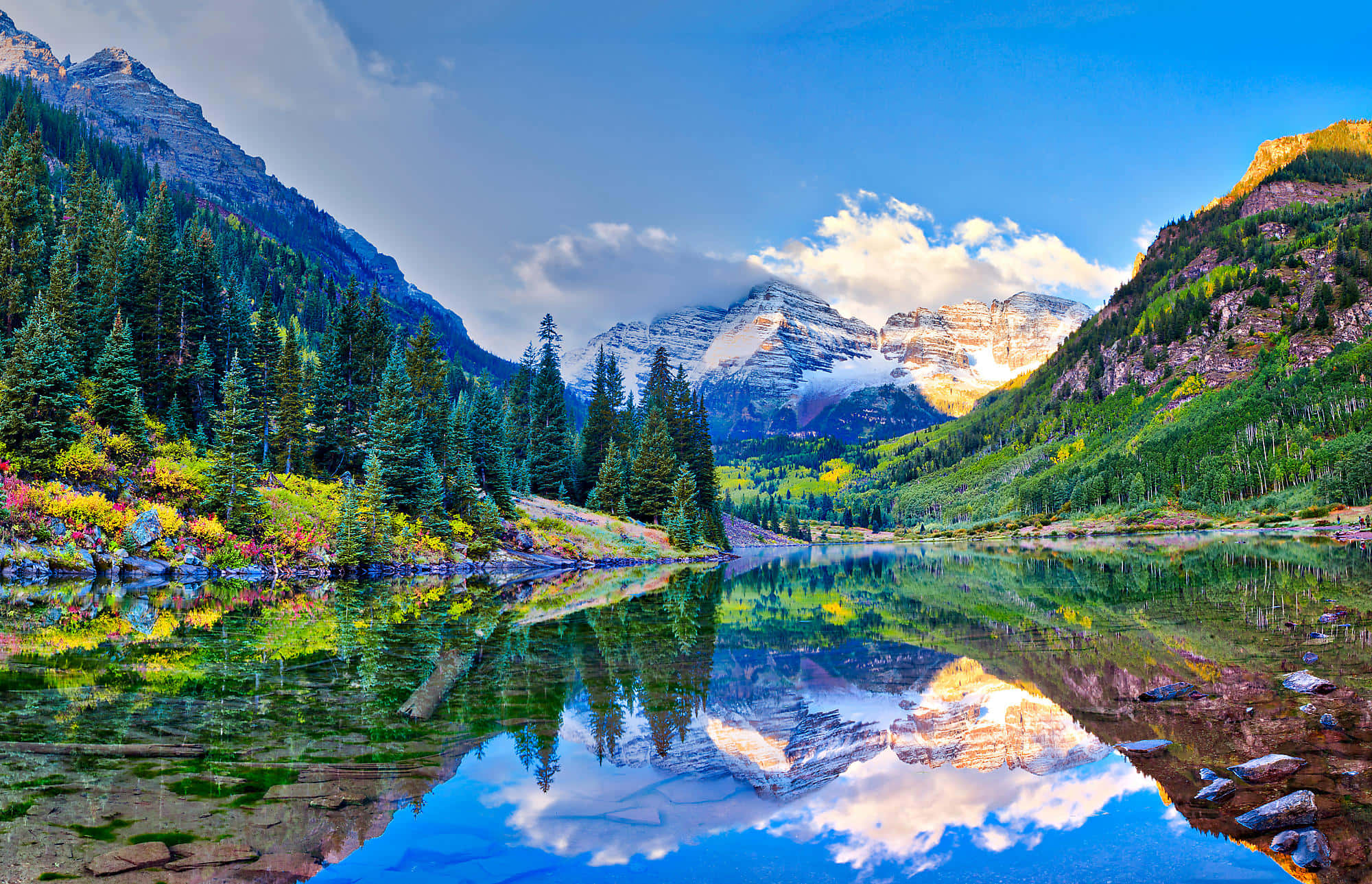 Colorado 桌布 壁紙 — 寧靜的山湖在晴朗的藍天白雲下，倒映著積雪的山峰和常綠森林。
