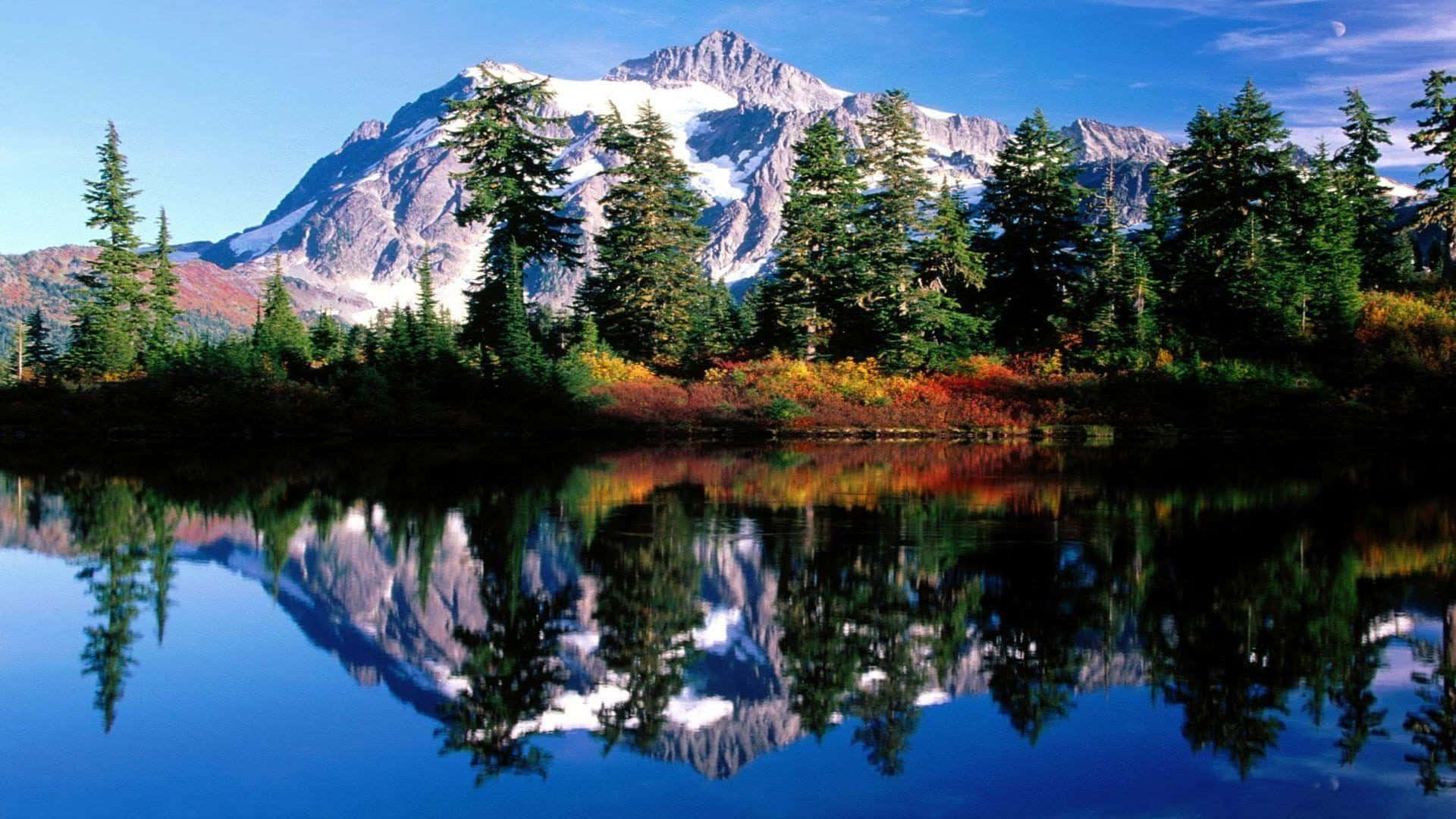 Montana 桌布 壁紙 — 寧靜的山湖映照著積雪的山峰和秋天的樹木，在清澈的藍天下有一彎新月。