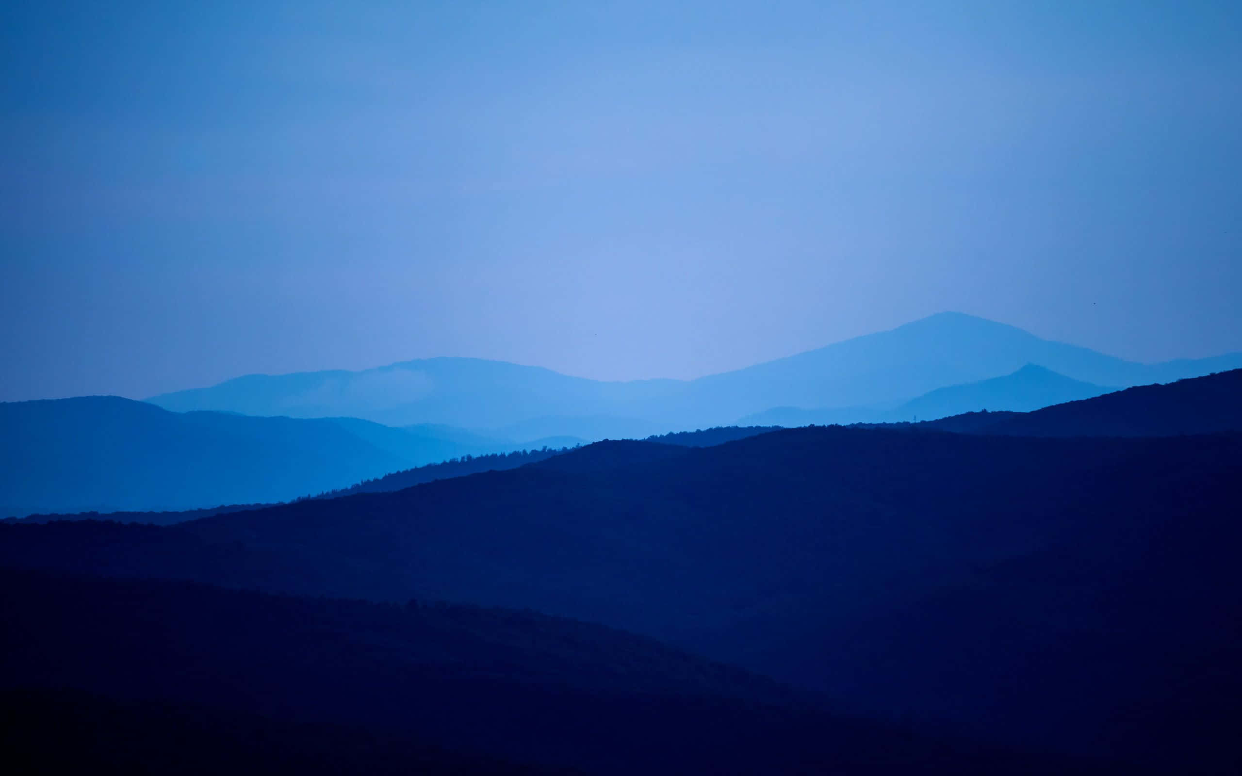 Mountain Landscape 桌布 壁紙 — 寧靜的山脊在暮色天空下融入大氣般的藍色薄霧中。
