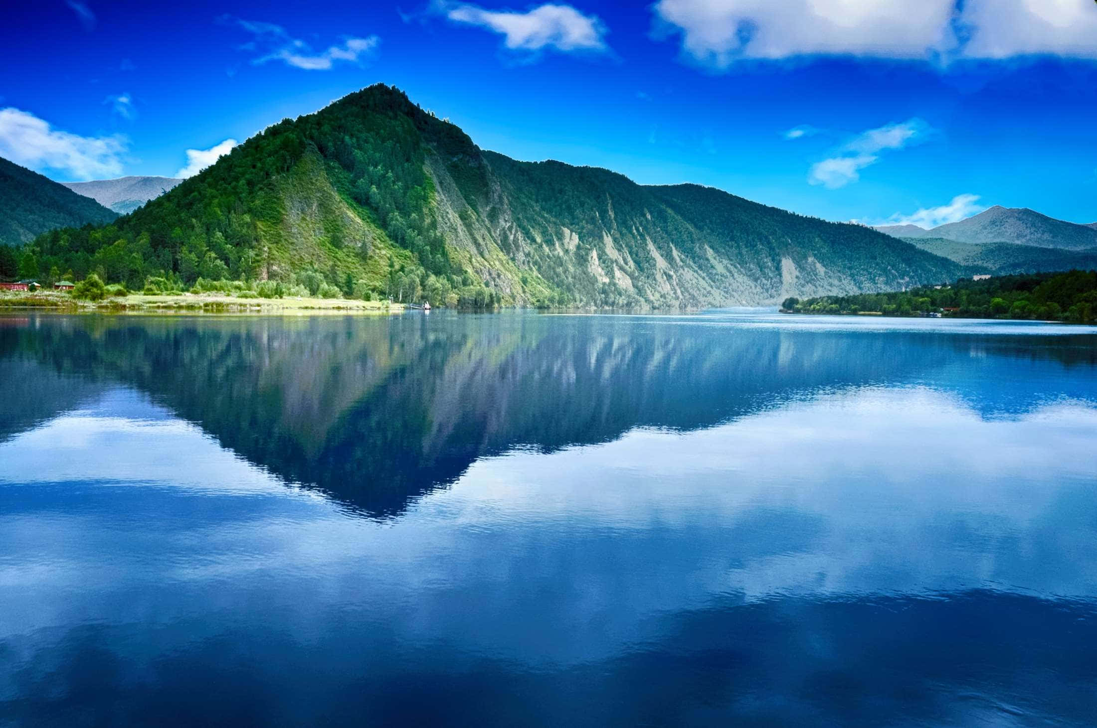山景 桌布 壁紙 — 寧靜的山間湖泊在明亮的日光下映照出充滿活力的藍天和鬱鬱蔥蔥的綠色山峰。