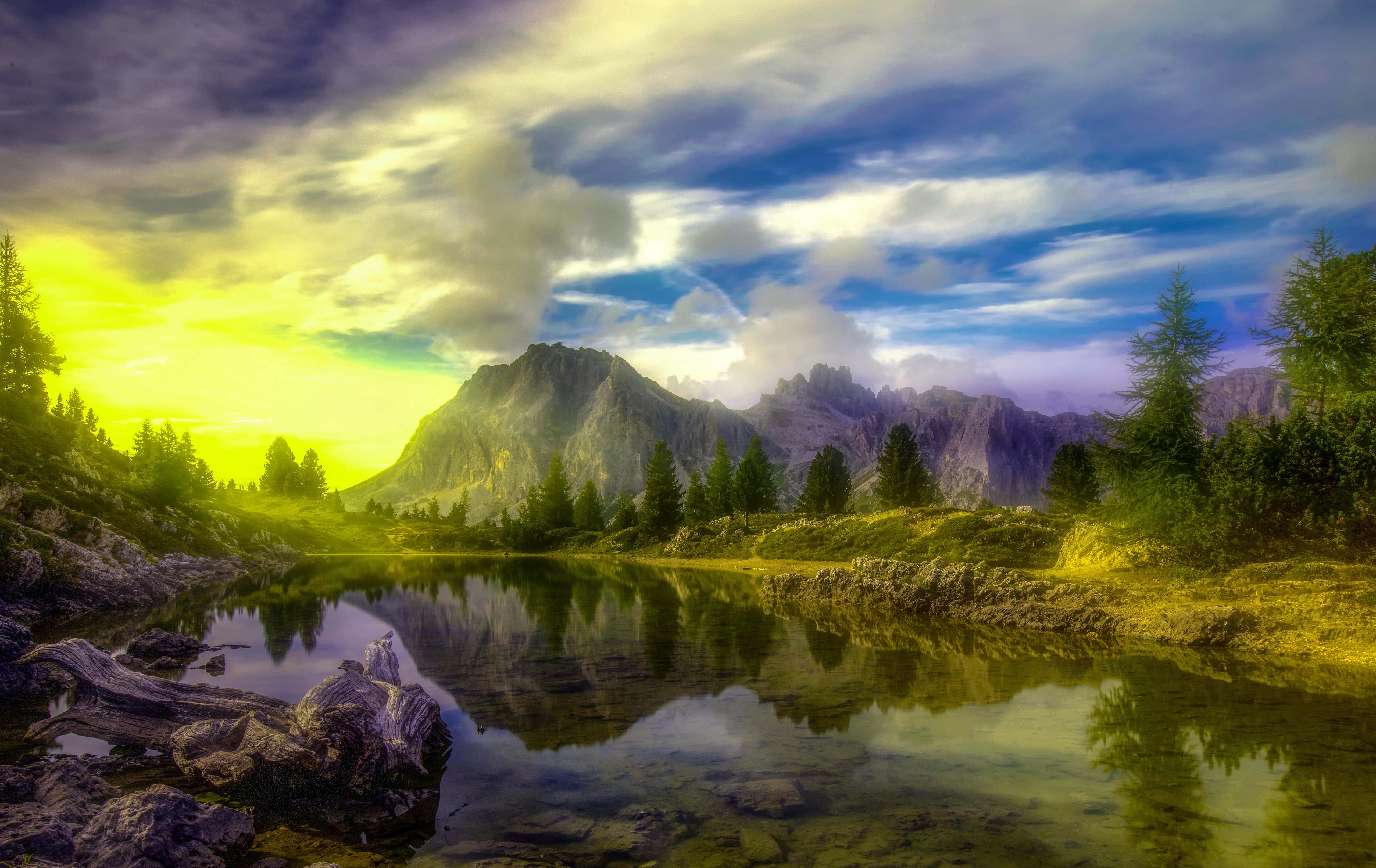 Skyrim Landscape 桌布 壁紙 — 寧靜的山間湖泊映照出崎嶇的山峰，天空佈滿金色雲彩，呈現壯麗的日落景象。