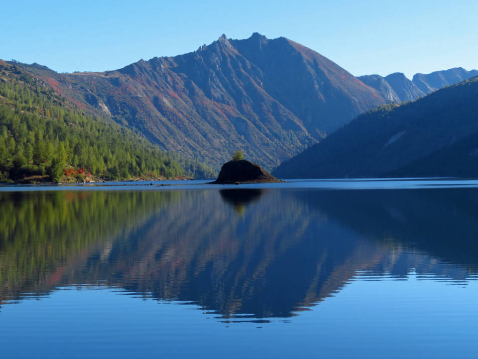 Beautiful Blue 桌布 壁紙 — 寧靜的山間湖泊映照出鋸齒狀的山峰和秋色森林，天空湛藍清澈。