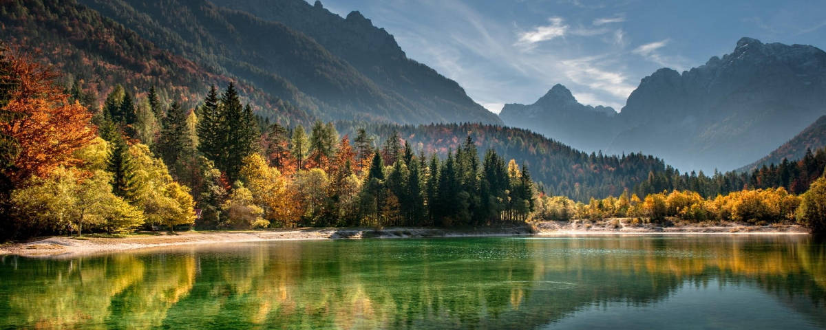 Lake View 桌布 壁紙 — 寧靜的山間湖泊映照著秋樹和鋸齒狀山峰，天空湛藍清澈。