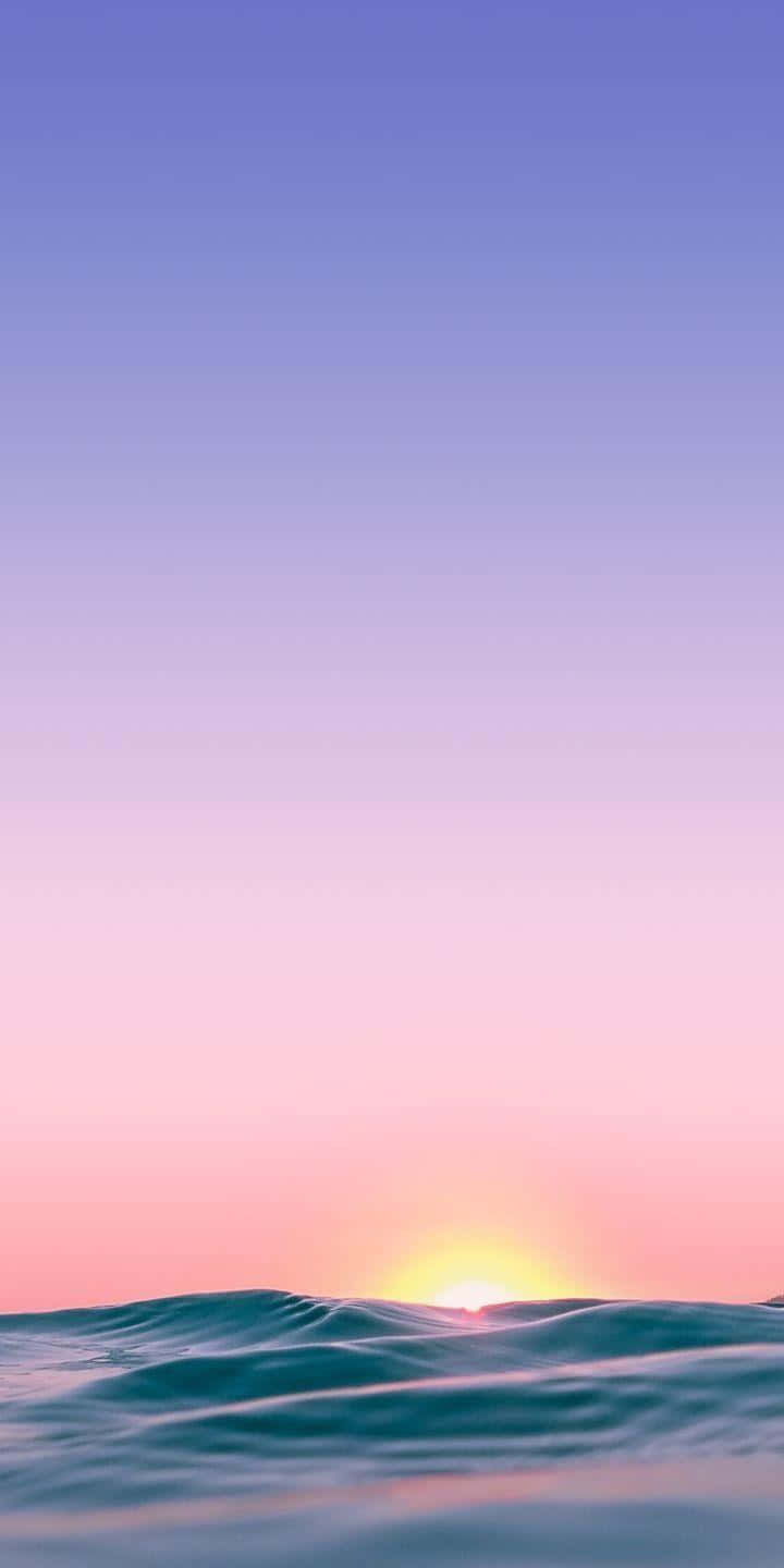 Sunrise iPhone 桌布 壁紙 — 寧靜的日出，平靜的海浪之上，柔和粉紅、紫色和藍色的漸變天空。