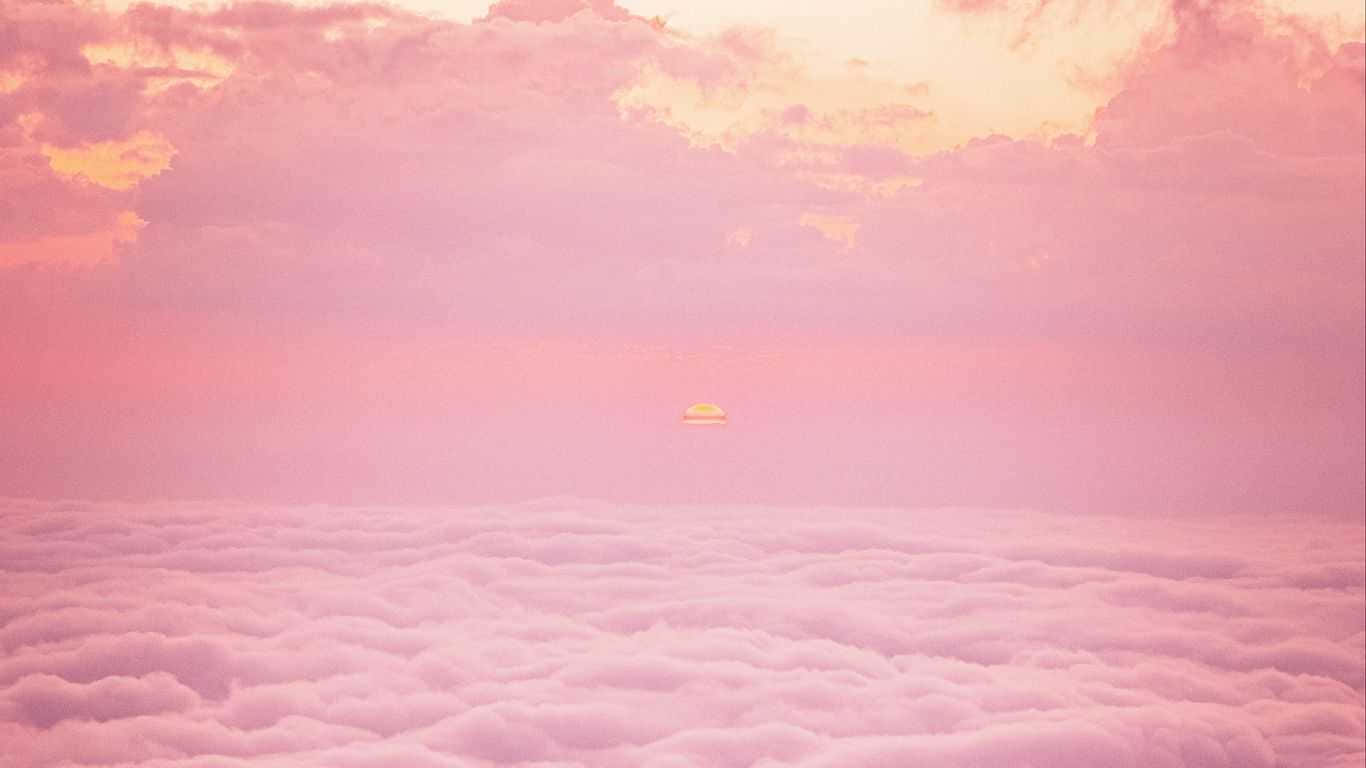桌布 壁紙 — 寧靜的日出從雲層之上將天空和雲朵染成柔和的粉紅色和金色色調。