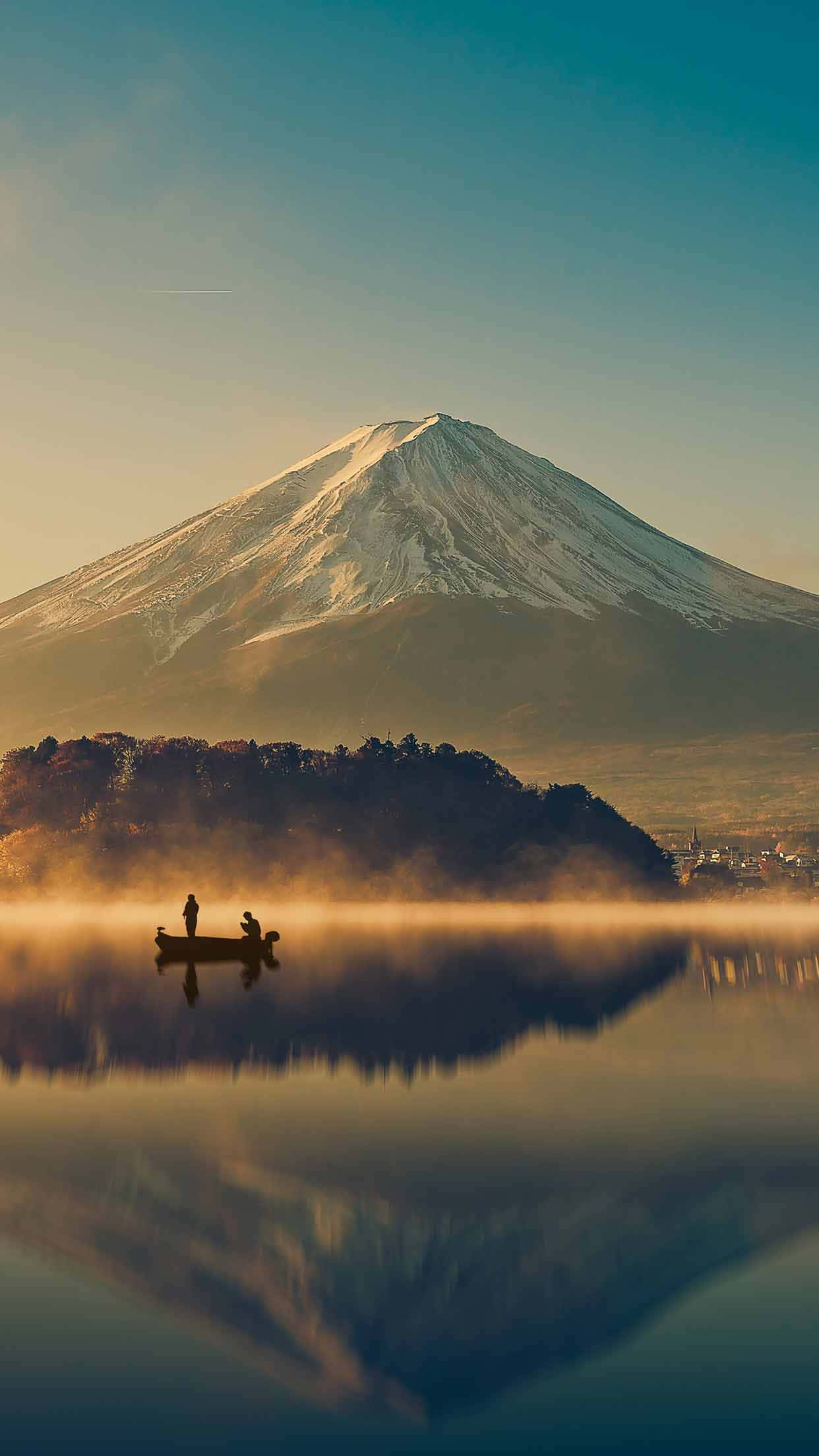 日本 桌布 壁紙 — 寧靜的日出映照著積雪的富士山，兩人在霧氣瀰漫的湖上划船，湖面倒映著雄偉的山峰。