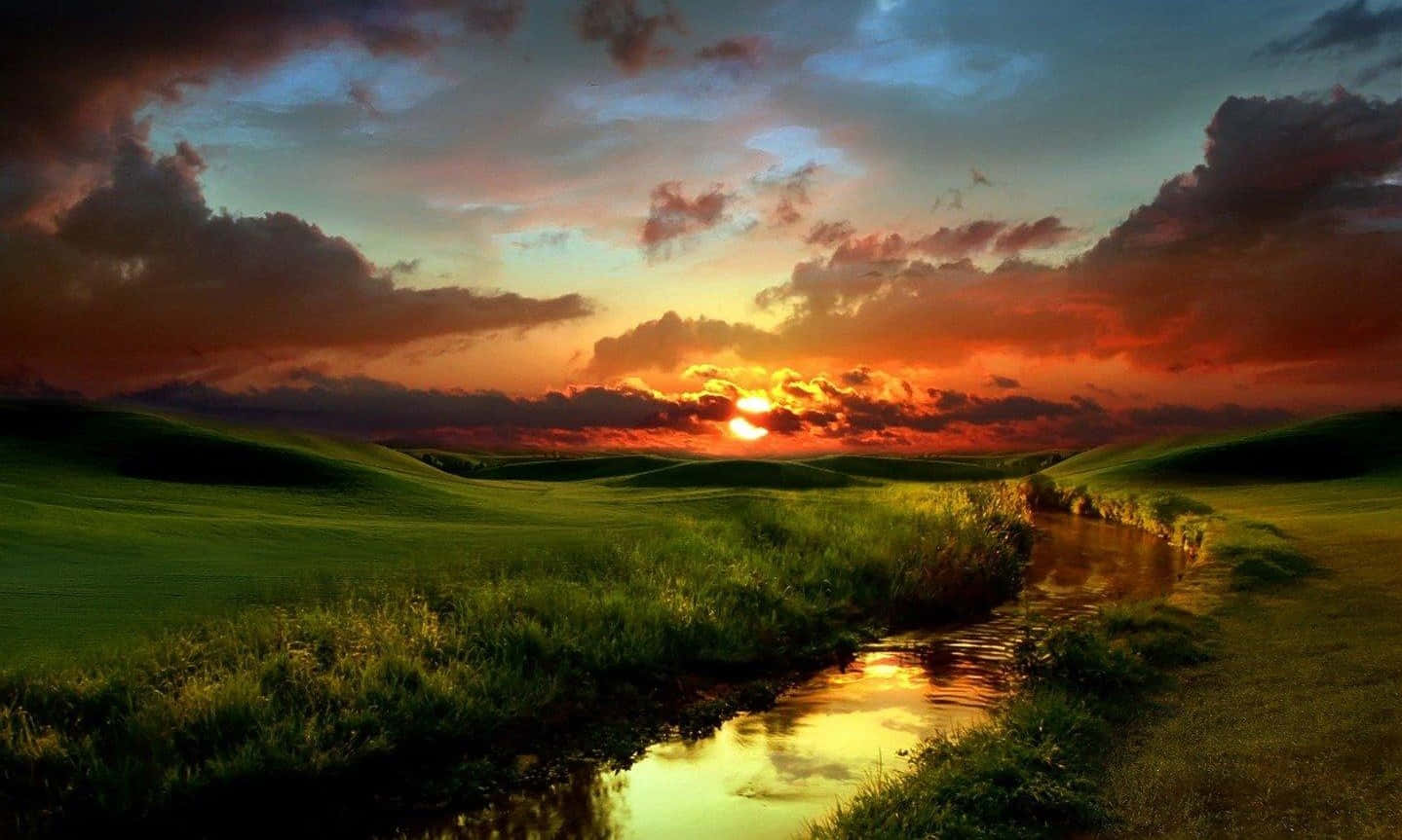 Sunset Landscape 桌布 壁紙 — 寧靜的日落，映照在起伏的綠色山丘上，蜿蜒的小溪反射著火紅的橙色雲彩。