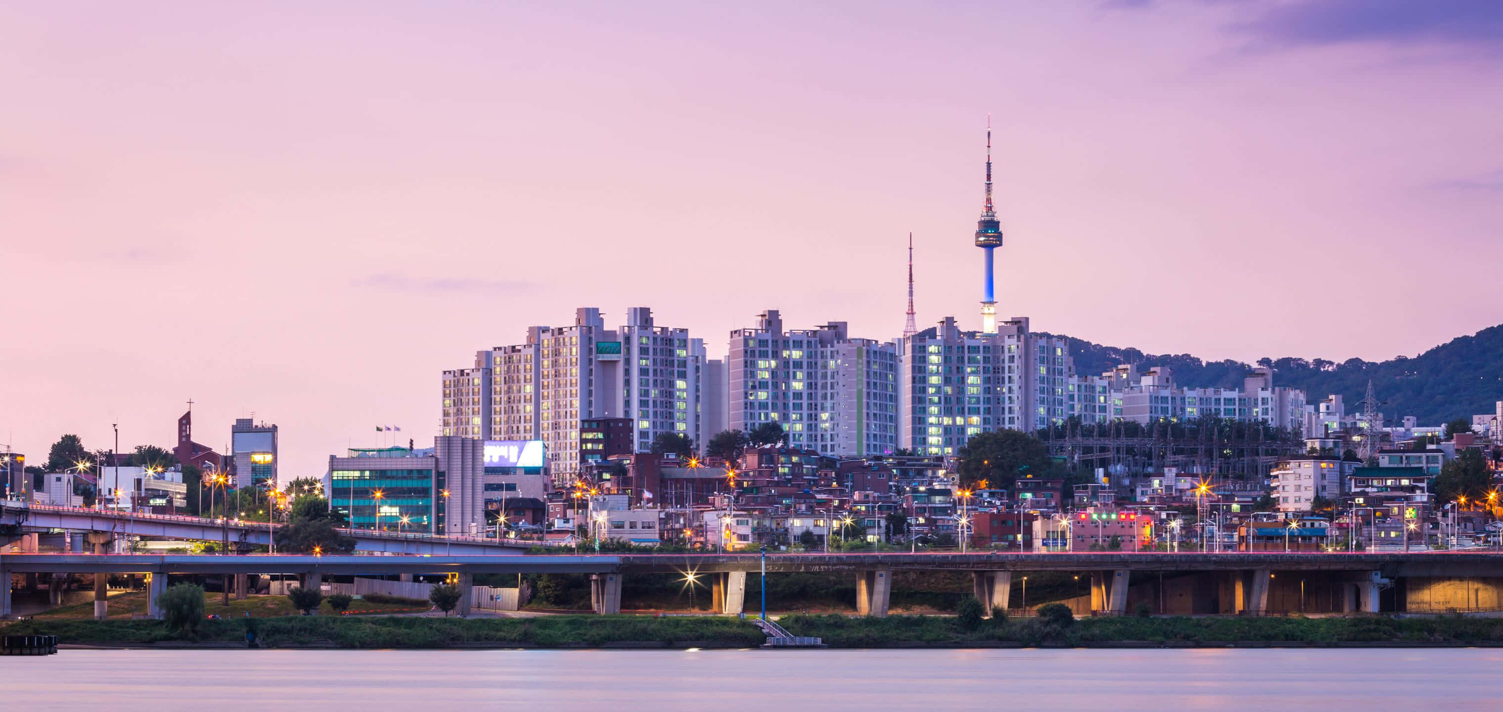 3040x1440 桌布 壁紙 — 寧靜的暮色城市景觀，河流反射橋樑和建築物的燈光，在柔和的紫色天空下。