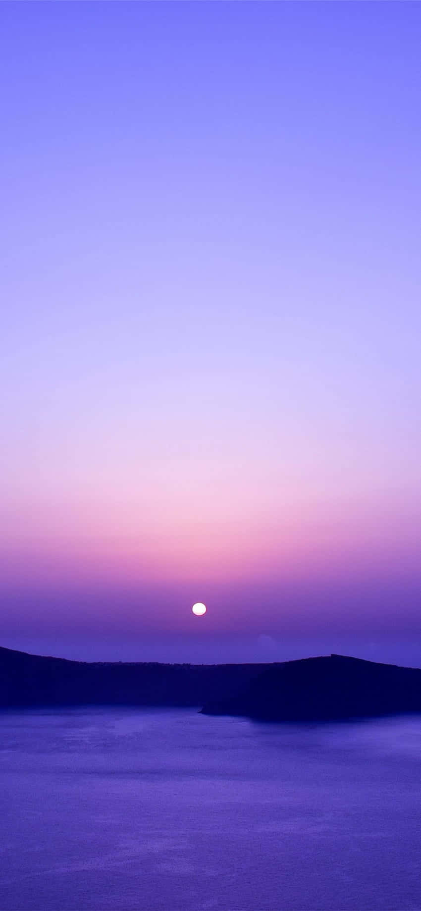 桌布 壁紙 — 寧靜的暮色場景，一輪發光的月亮懸掛在平靜的紫色海洋和黑暗的剪影懸崖之上。